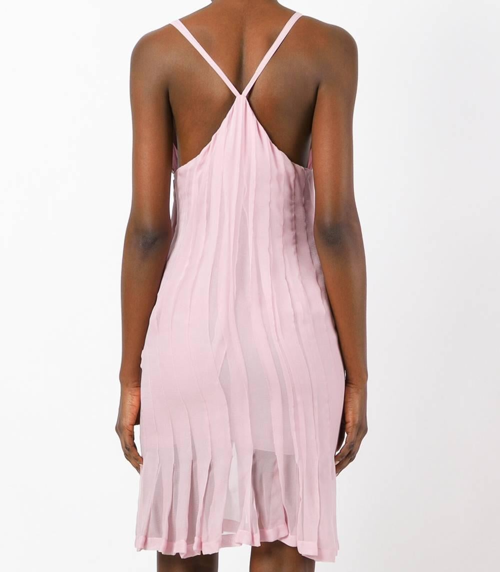 Delicate Chanel pink silk pleated skirt dress. It features a deep V neck, a sleeveless design, back crisscross straps, an empire line silhouette, a concealed side zip fastening, a knee length and an interlocking CC logo to the front. The item is