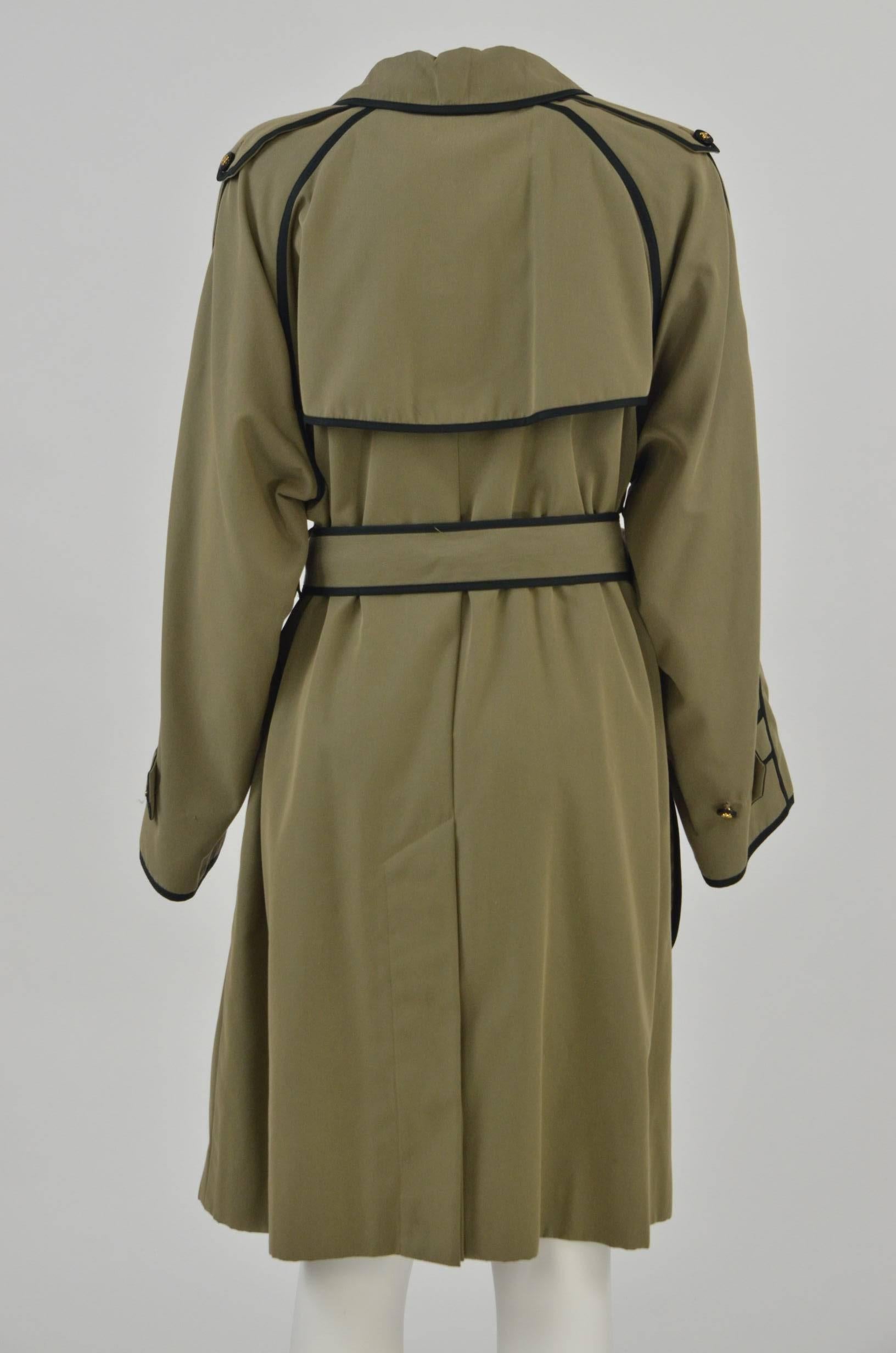 Khaki green cotton trench coat by Chanel featuring a peter pan collar, single chest flap, a contrast double-breasted front button fastening, black trim detailing, two side buttoned flap pockets, flap at the rear of the neck, rear vent and long