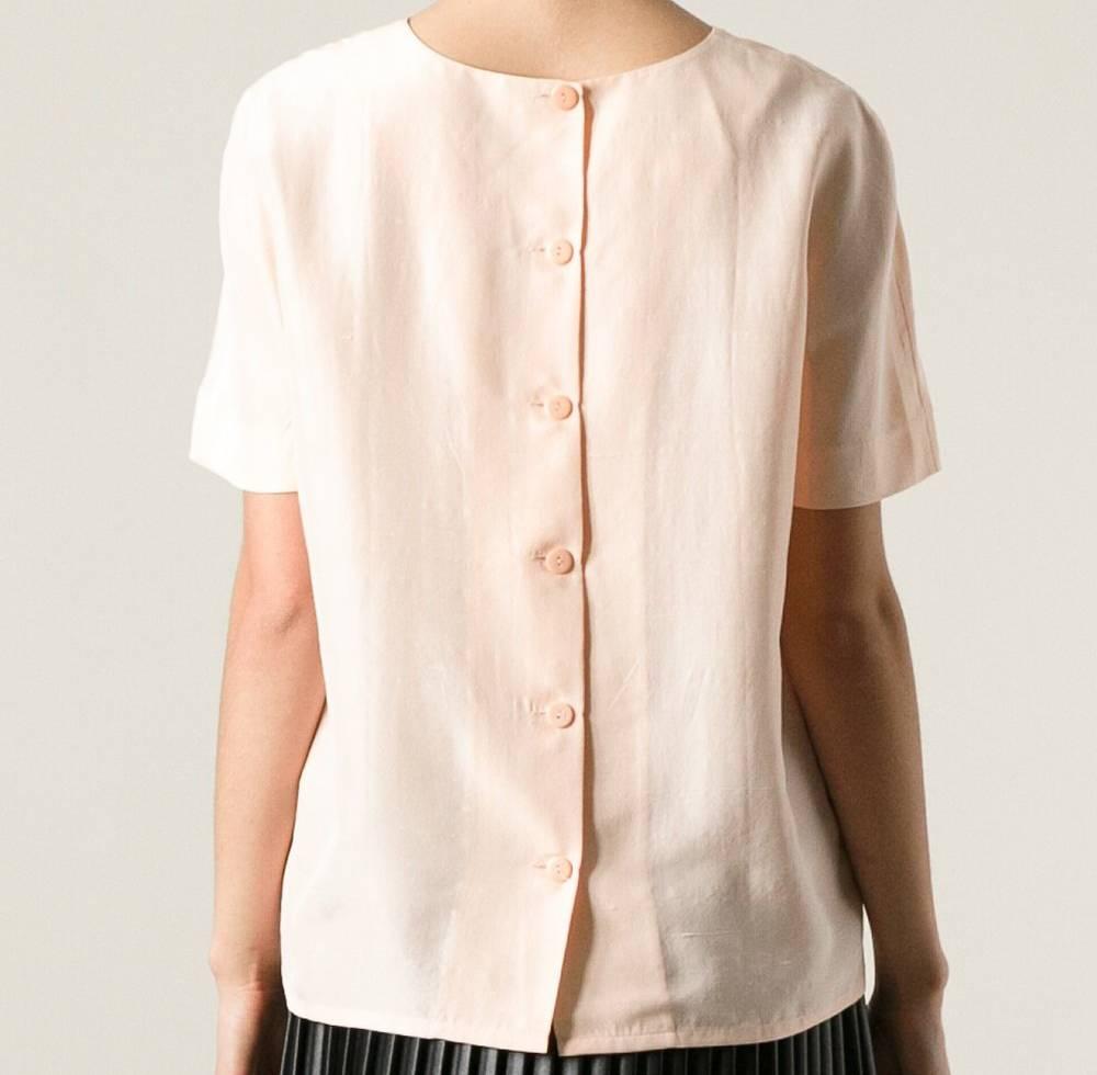 Delicate blouse 100% silk by Céline, T-shirt model, in a nude pink color. Round-necked, with short sleeves and straight cut. It features a closure made of row of six pink buttons on the back. The item is vintage, it was produced in the 2000s and is