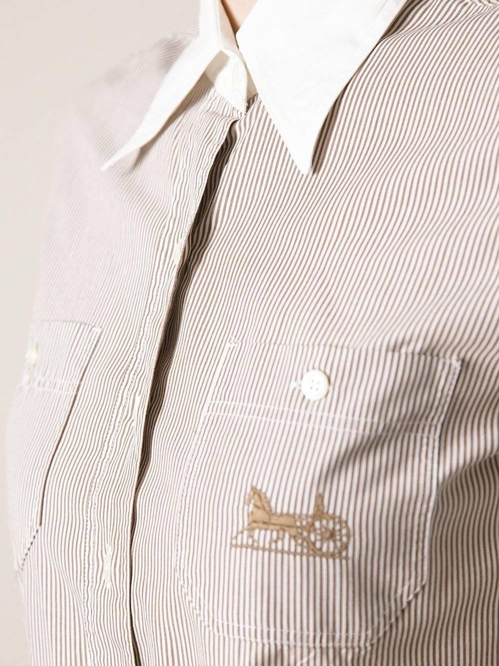 Short-sleeved Céline shirt 100% cotton, striped in white and brown, with an embroidered horse logo on the left pocket. It features a white collar, frontal buttons closure and two pockets on the breast.  The item is vintage, it was produced in the