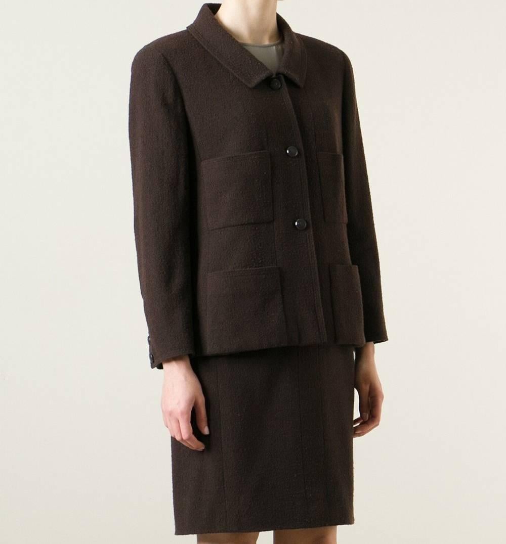 Classic Chanel two-piece suit in brown wool. The blazer features a classic collar, a front dark button fastening, patch pockets, long sleeves, button cuffs and a boxy fit. The skirt features a knee length and a straight fit. The item is vintage, it