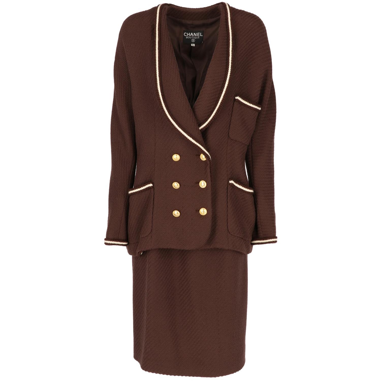 Chanel brown wool skirt suit. It features a beautiful jacket with long sleeves, double-breast lacing and shawl lapels. It has three applied pockets and all edges are finished by a trimming. Midi skirt with a side rip lacing with three buttons and