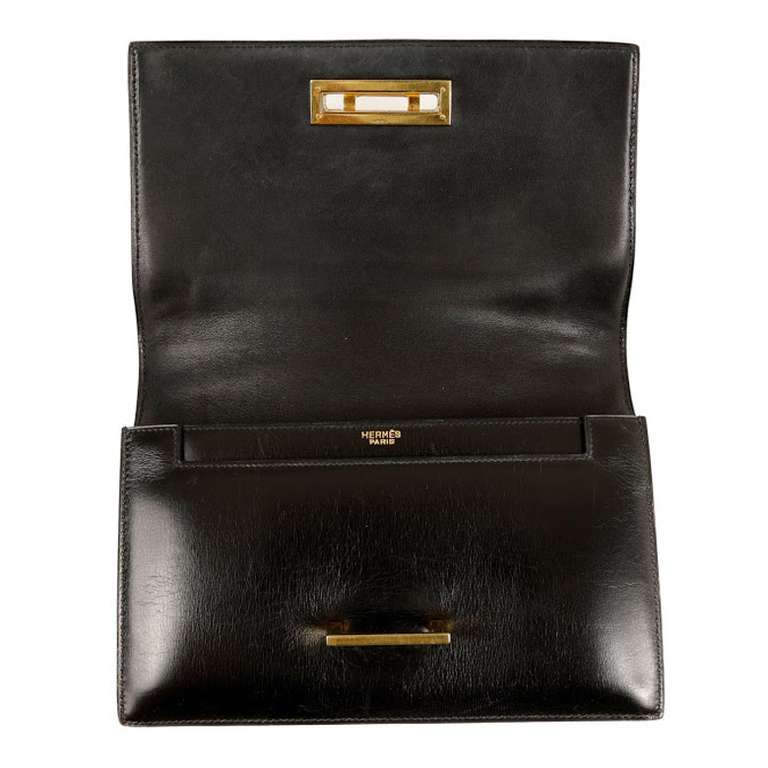 This Hermes Vintage Black Quito Bag is in pristine condition. It has black calfskin patent-leather with yellow metal hardware, and a convertible shoulder strap.