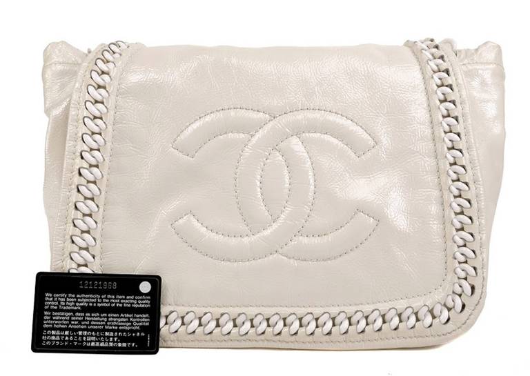his Authentic Chanel Pearl Patent Leather Resin Chain Flap Bag is in pristine condition, appearing never carried. Glossy pearl white patent leather has a lightly crinkled texture and slight metallic sheen.  White resin chain borders the flap and