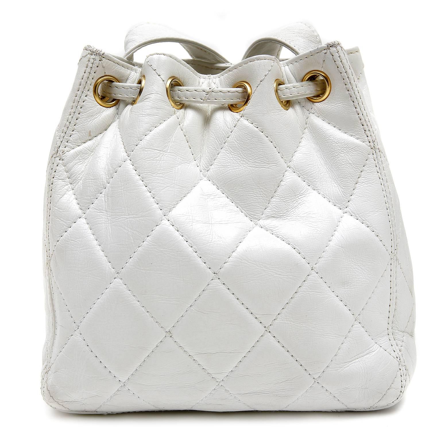 Chanel White Lambskin Drawstring Bucket Bag is in nearly pristine condition.  Petite in stature, the classic bucket style is perfect for traveling with just the essentials. 
 
White lambskin is quilted in signature Chanel diamond stitched pattern.