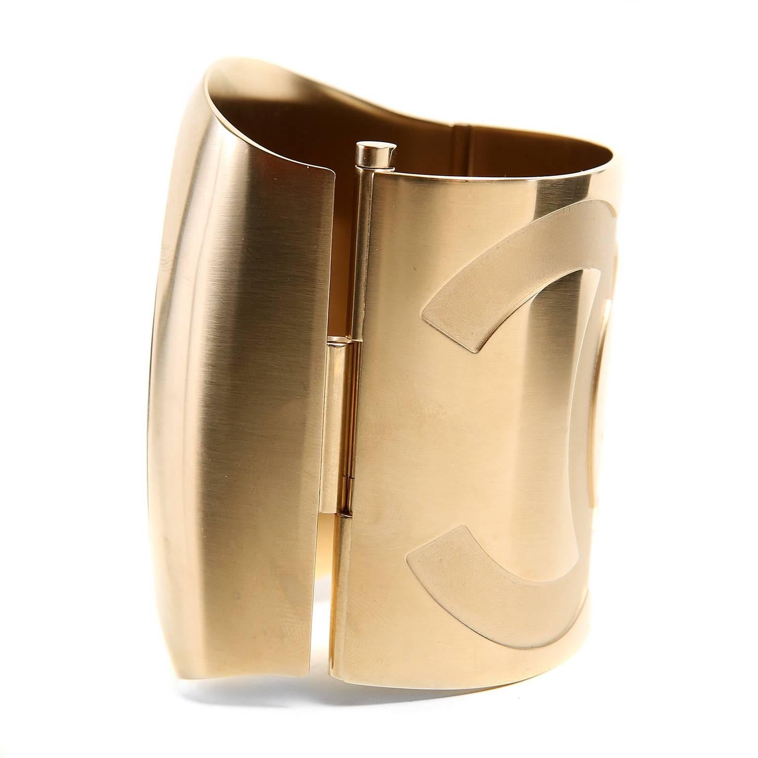 hanel Gold Matte Hinged Cuff is in pristine condition.  Collectible and versatile, this striking cuff can be worn with a tee and jeans or a formal gown.  The perfect gift for a Chanel lover.
 
 Large gold tone cuff has colossal tonal interlocking
