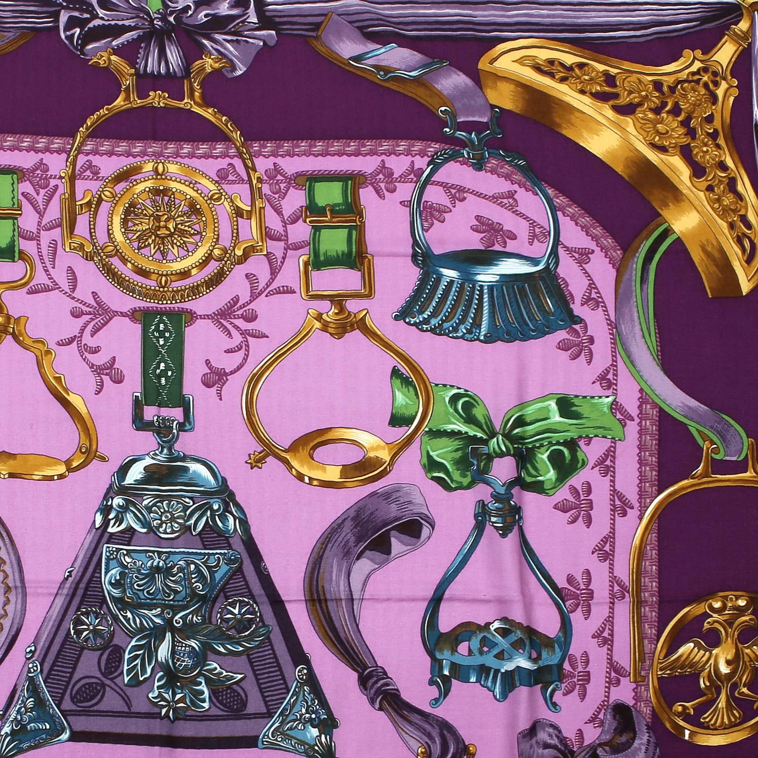 Hermès Purple Etriers Cashmere and Silk Shawl- Pristine
  The equestrian themed design features antique stirrups, highlighting the intricate metalwork and exquisite details.       Varying shades of purple and gold with a bright green border.   65%