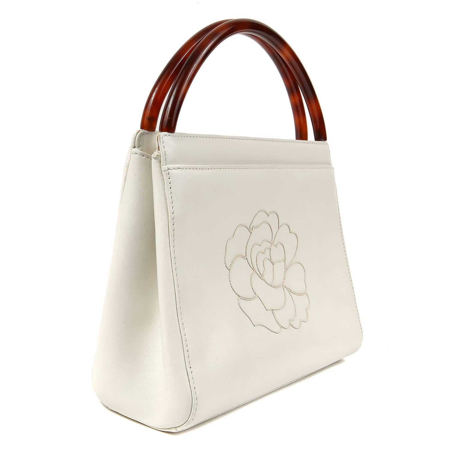 Chanel Vintage White Leather Camellia Day Bag- EXCELLENT
 The rounded Bakelite handles add interest to this unique and collectible bag.

Snowy white leather has the iconic camellia flower stitched on the front.  A magnetic snap accesses the white