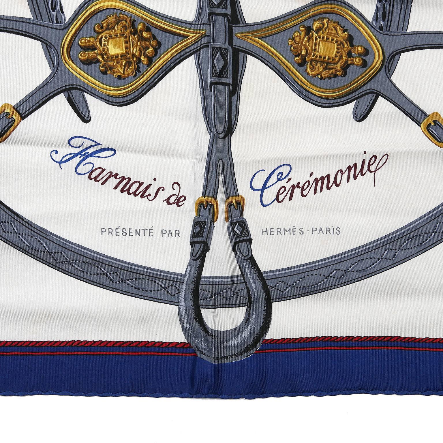 Hermès Blue Silk Harnais de Ceremonie Scarf is in pristine condition. 

Translating to “Harness Ceremony” this print has an equestrian theme.  White background with royal blue trim. Grey, gold, and burgundy accents.  Made in France.

