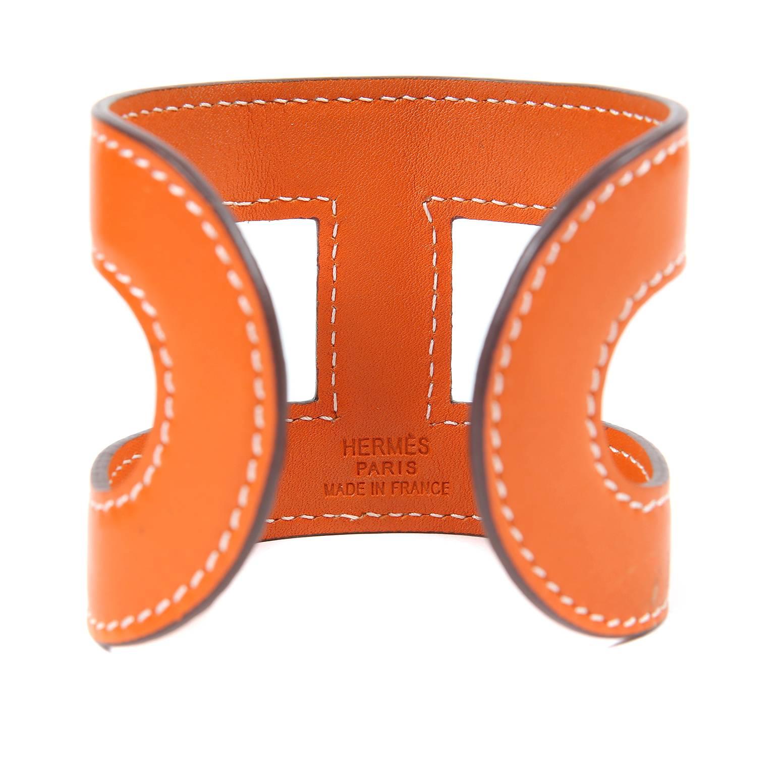 Hermès Orange Leather H Cuff is in excellent condition.  Wide leather bangle style has contrasting white stitching.  Cut out design creates the iconic “H” of Hermès.  Made in France.
A100