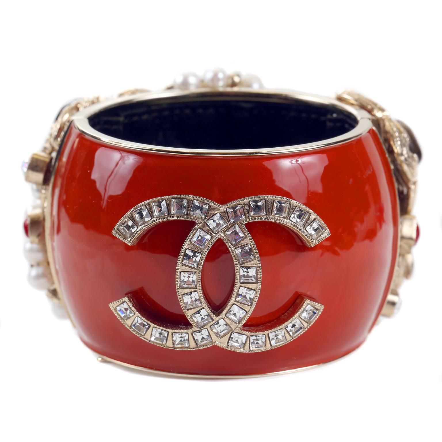 This authentic Chanel Jewel Encrusted Byzantine Collection Bangle Bracelet is pristine.  One of perhaps three in existence, this stunning bracelet is highly collectible.  
Rust colored enamel bangle is covered in pearls, gem stones and icons on one