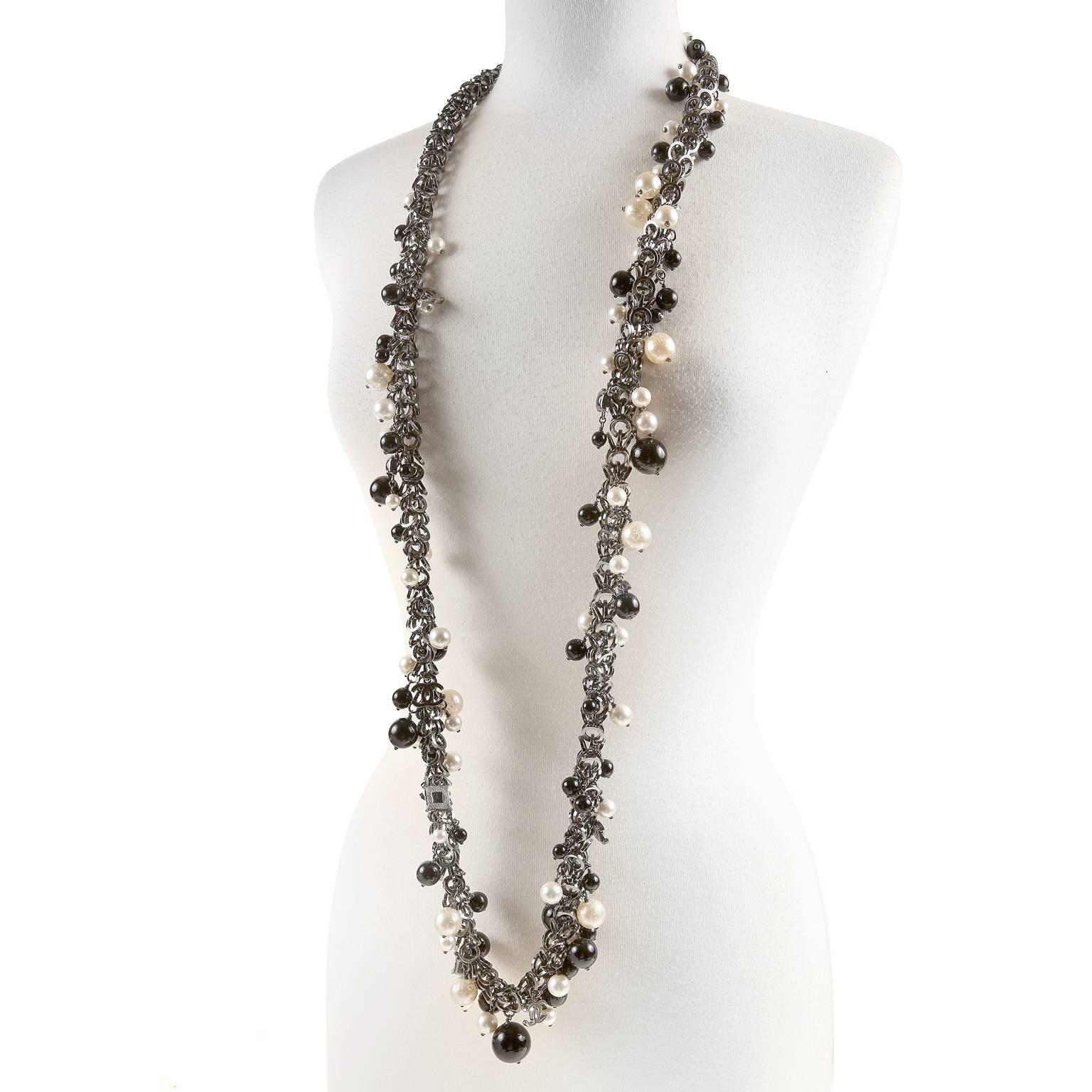 This authentic Chanel Black and White Pearl Long Necklace is pristine.  Perfect for any collection, this unique and versatile necklace can be worn with everything.
Dark silver linked circles create the substantial chain.  Various sizes of black,