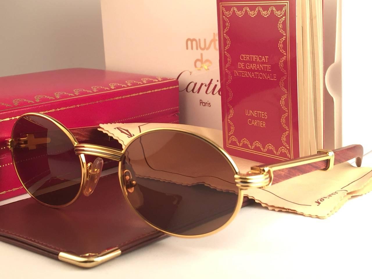

New Original Rare Yellow and White Gold 1992 Cartier classy Giverny Sunglasses with rosewood temples and honey brown spotless uv protection lenses. 
Frame with the front and sides in yellow gold. 
All hallmarks. 
Gold Cartier signs on the ear