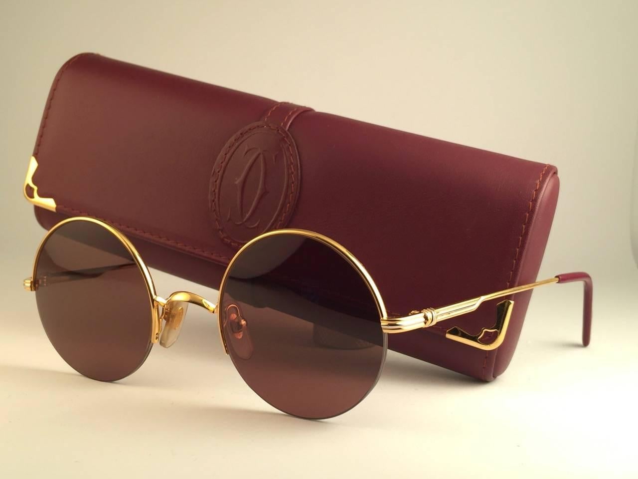 
New 1990 Cartier Mayfair 45mm half frame sunglasses with brown (uv protection) lenses. 
Frame is with the front and sides in gold. All hallmarks. Cartier gold signs on the ear paddles. These are like a pair of jewels on your nose. 
Beautiful design