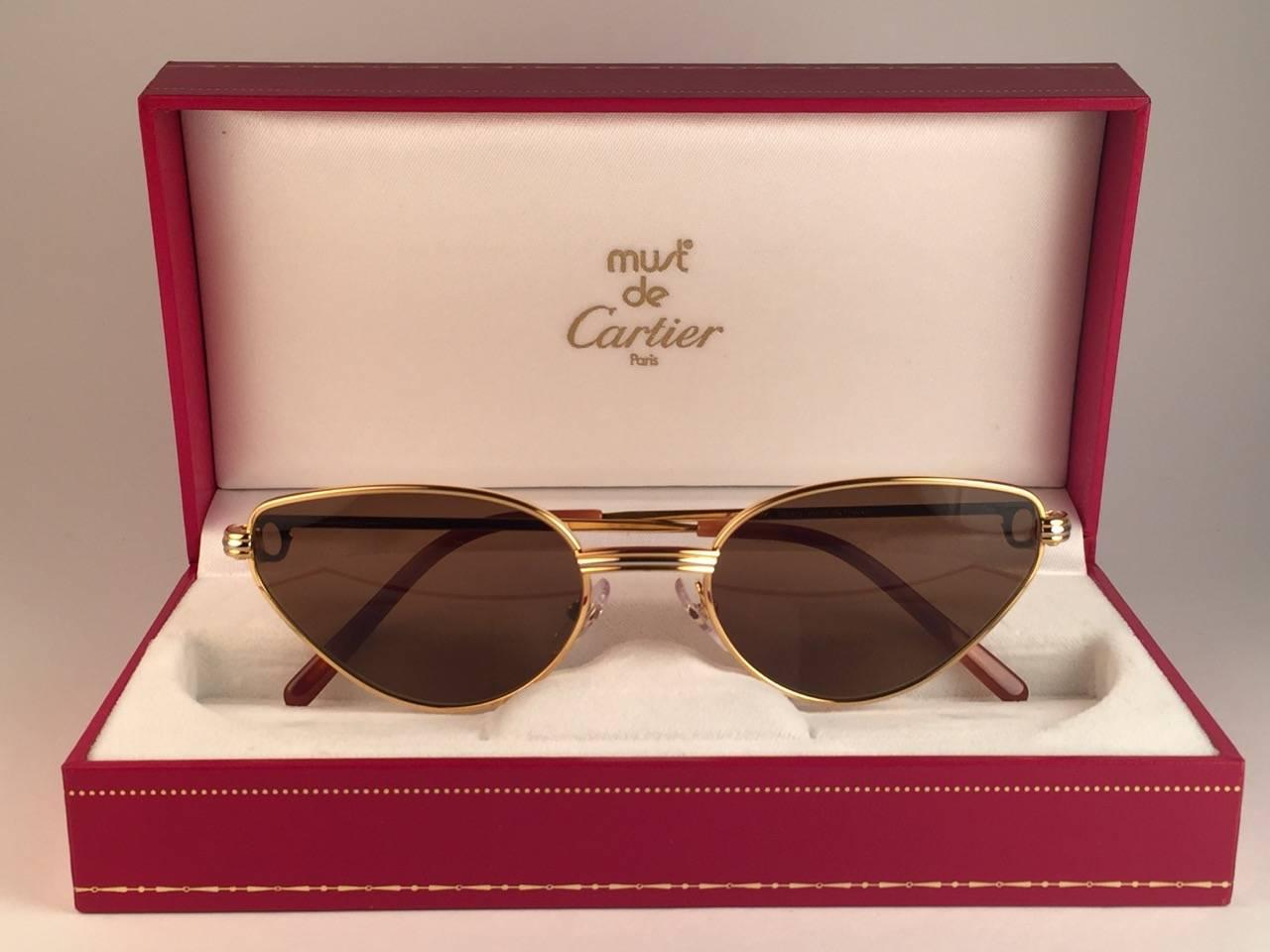 New 1988 Cartier Rivoli Vendome Cat Eye Sunglasses with new honey brown cartier (uv protection) lenses. 
The cat's eye frame is with the front and sides in yellow and white gold. 
All hallmarks. Red enamel ear paddles. Both arms sport the C from