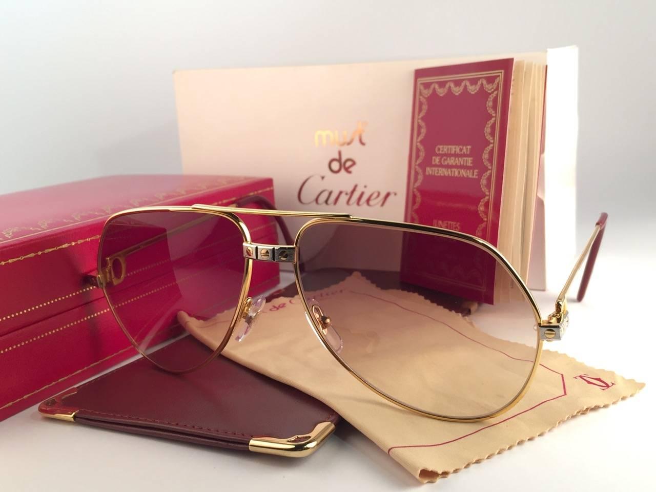 New from 1983!!! Cartier Aviator Santos Sunglasses with Brown Gradient (uv protection) Lenses.  Frame is with the famous screws on the front and sides in yellow and white gold. All hallmarks. Red enamel with Cartier gold signs on the ear paddles. 