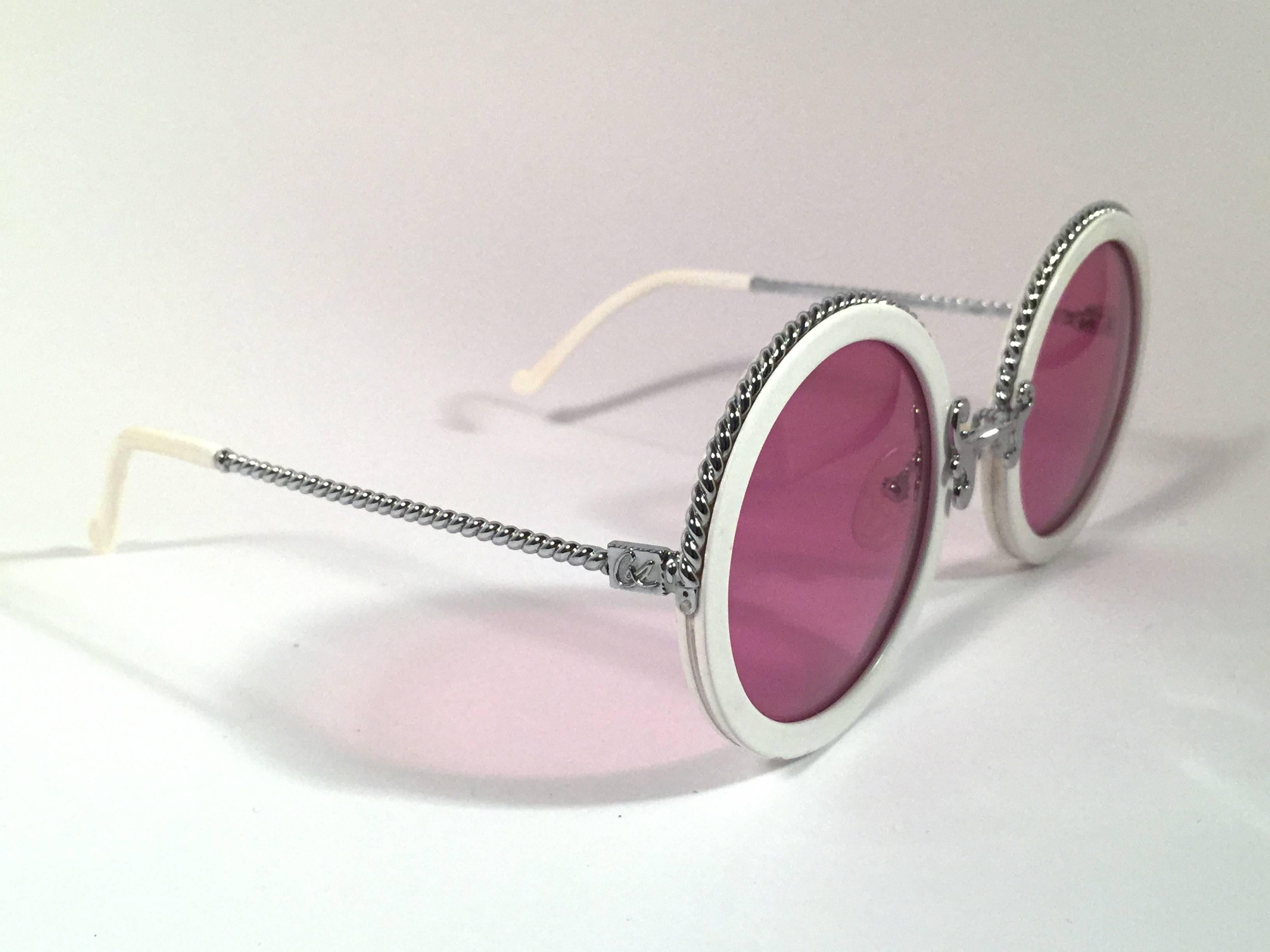 Superb & rare pair of New vintage Christian Lacroix sunglasses. 

White round with delicate silver accents frame holding a pair of spotless candy pink lenses.

New, never worn or displayed. Made in France.

