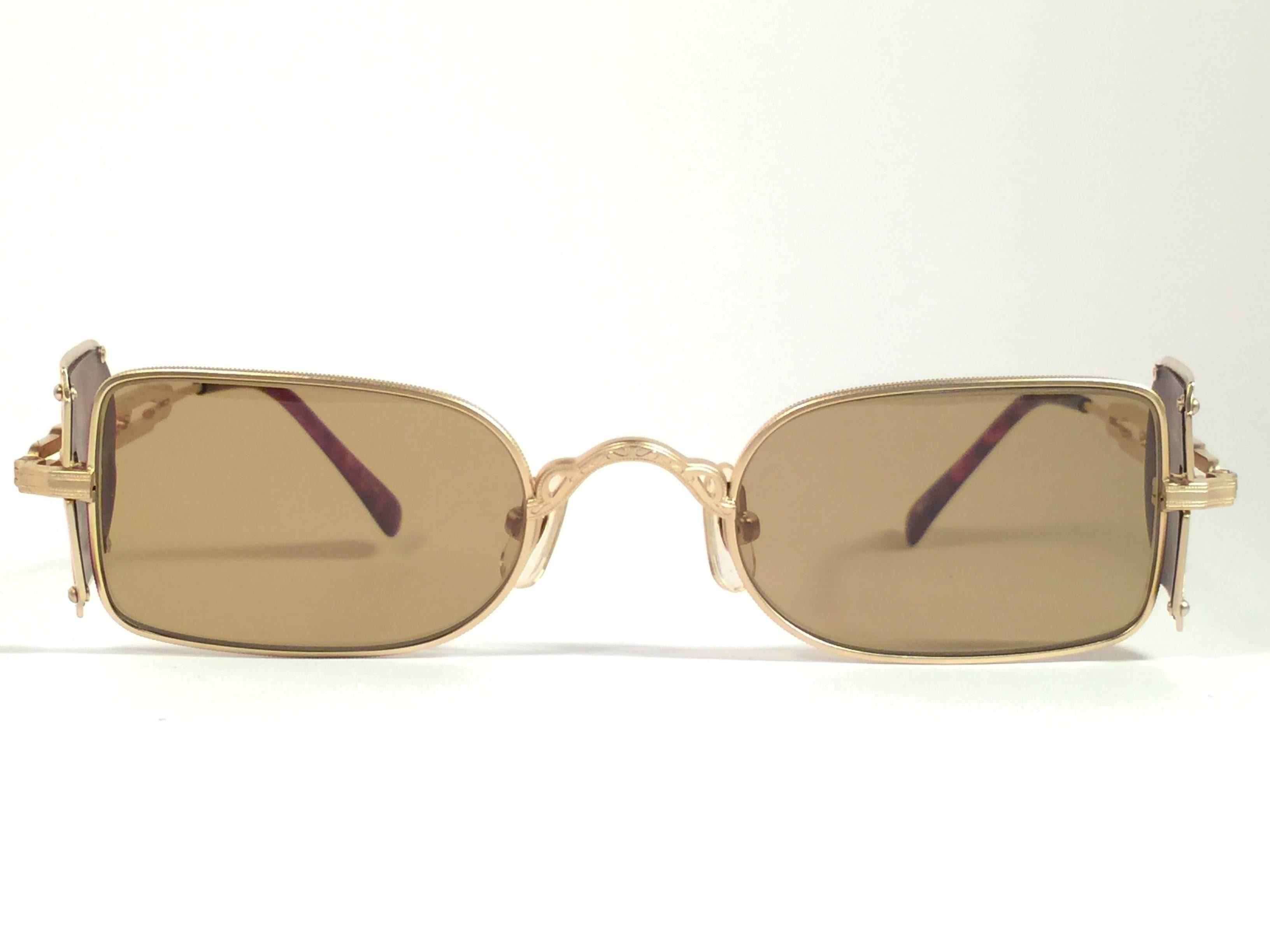 Cult brand Matsuda signed this ultra chic pair of rectangular gold matte frame with intricate detailed side cups sunglasses. 

Spotless medium brown lenses.

Superior quality and design. 

New, never worn or displayed. Made in japan.

MEASUREMENTS