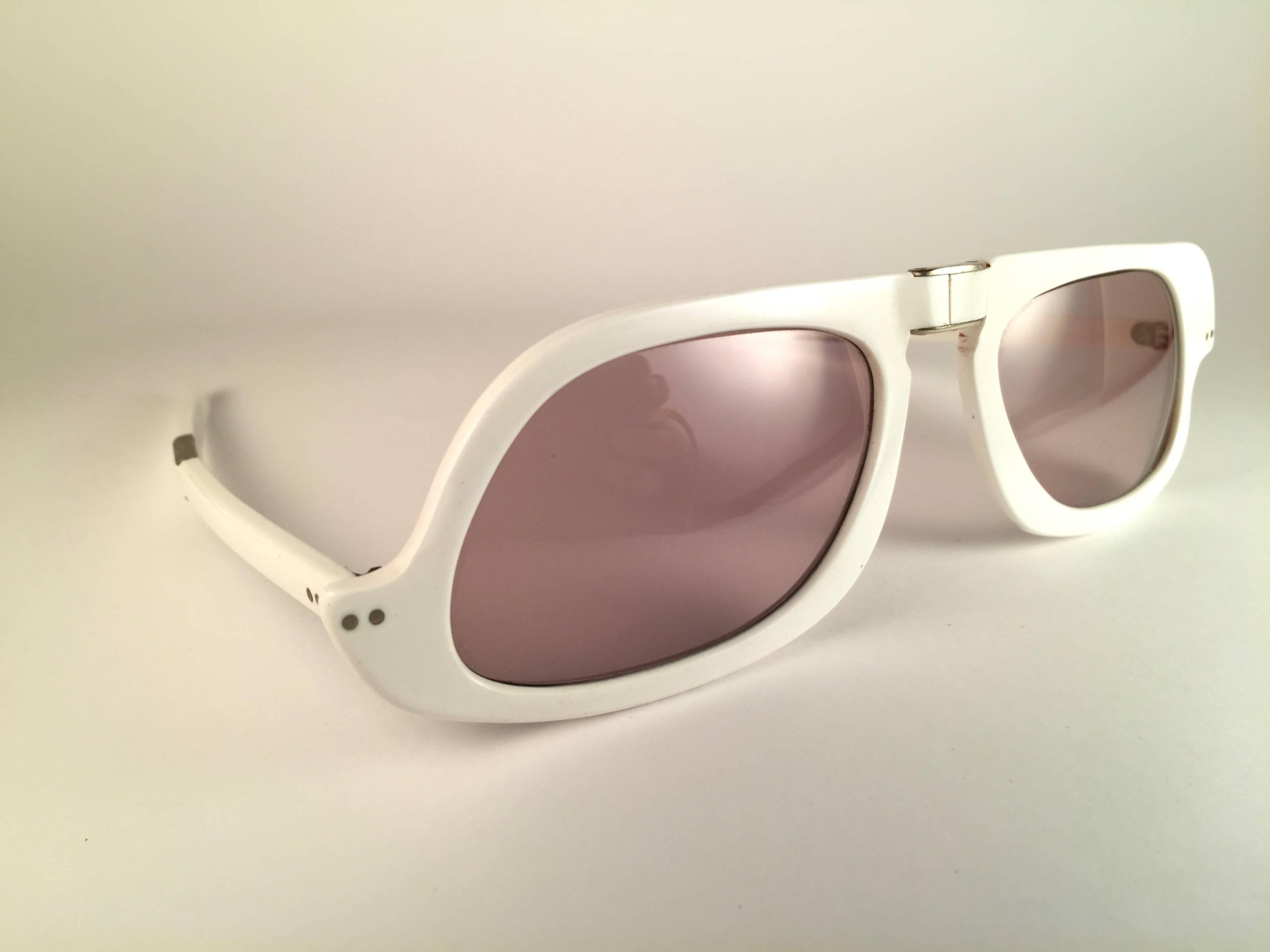 New vintage futuristic Pierre Cardin white foldable rectangular frame sporting a beautiful pair of pink/amber lenses. This pair have slight wear on them due to to nearly 60 years of storage.   
This pair of vintage Pierre Cardin is a unique piece