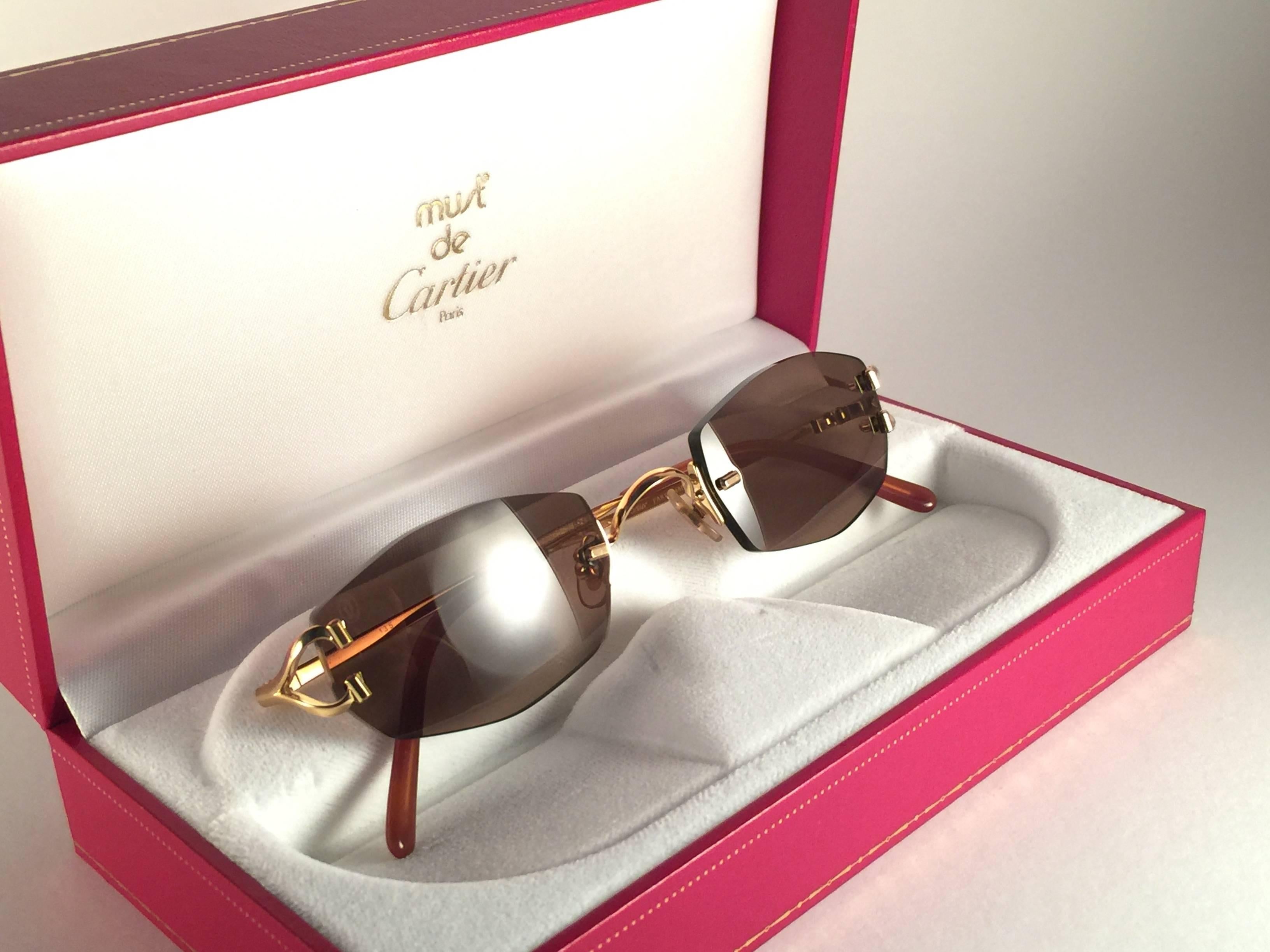 New 1990 Cartier Capri unique rimless sunglasses with brown original Cartier  (uv protection) lenses. Frame with the front and sides in gold.  All hallmarks. Cartier gold signs on the honey brown ear paddles. These are like a pair of jewels on your