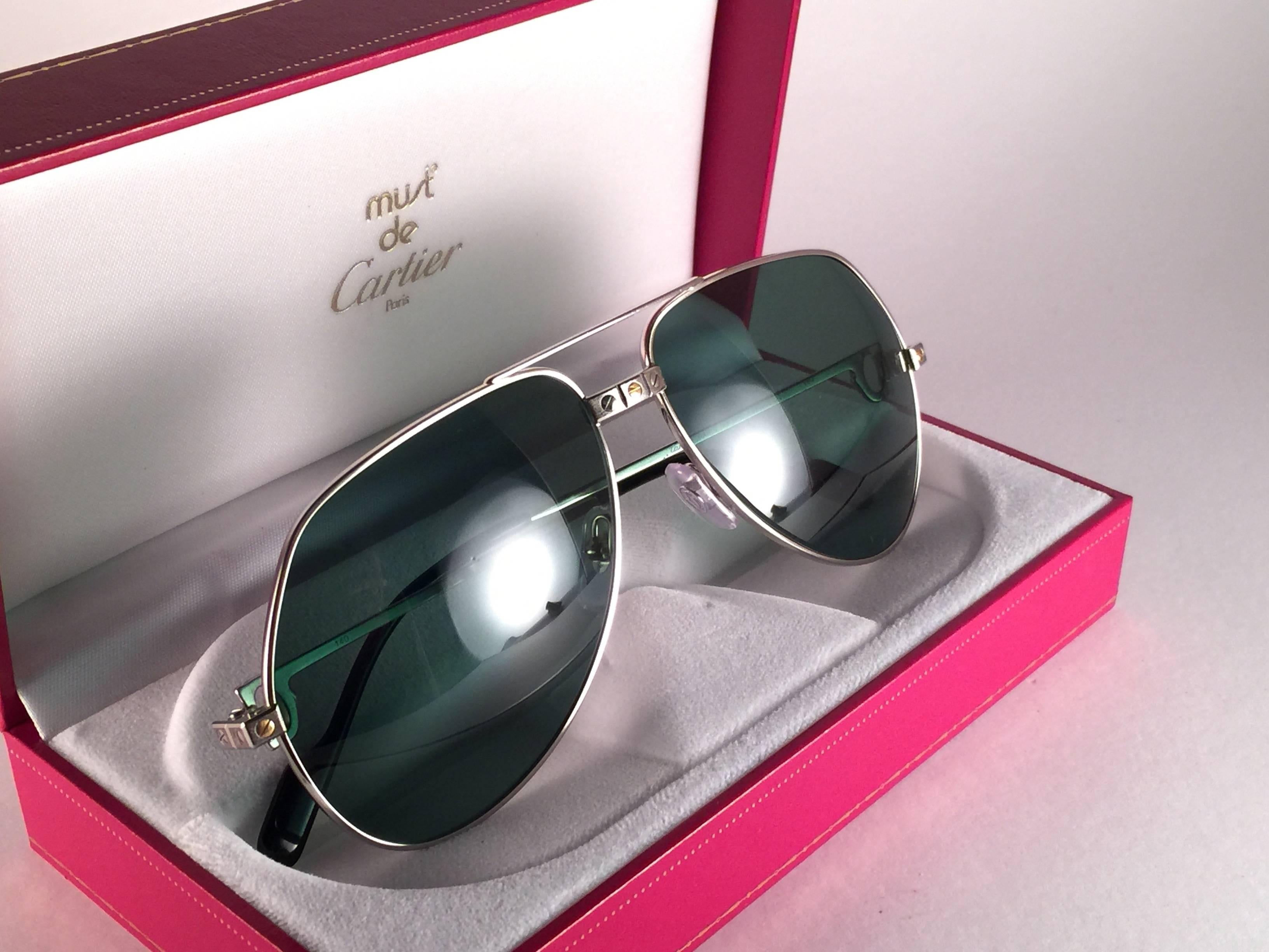 New from 1983!!! Cartier Aviator Santos 62Mm white gold sunglasses with dark grey original Cartier (uv protection) Lenses.  Frame is with the famous screws on the front and sides one in yellow and the other two in white gold. 
All hallmarks. Black