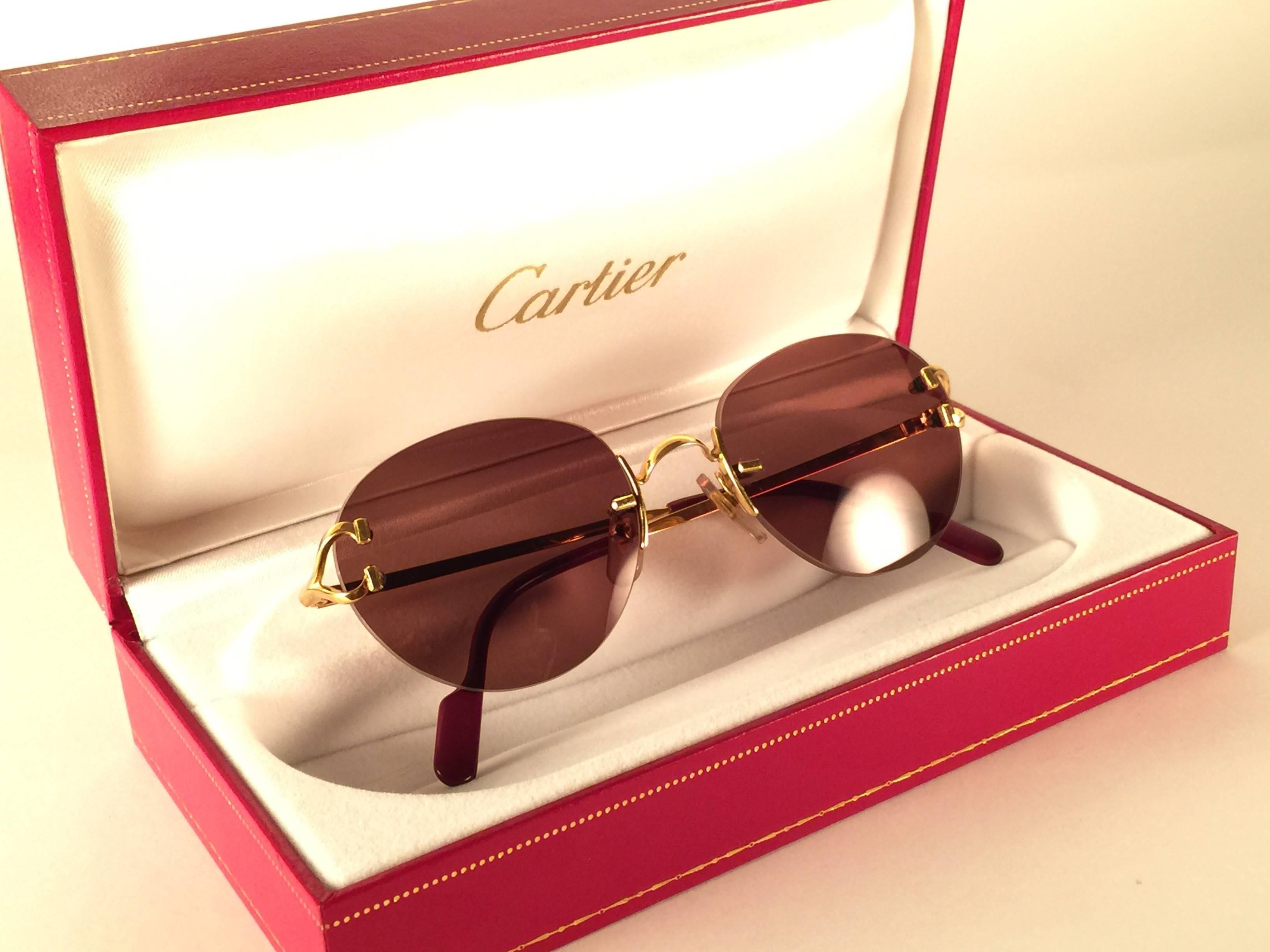 New 1990 Cartier Portofino unique rimless sunglasses with solid brown (uv protection) lenses. Frame with the front and sides in gold. All hallmarks. Cartier gold signs on the burgundy ear paddles. These are like a pair of jewels on your nose. 