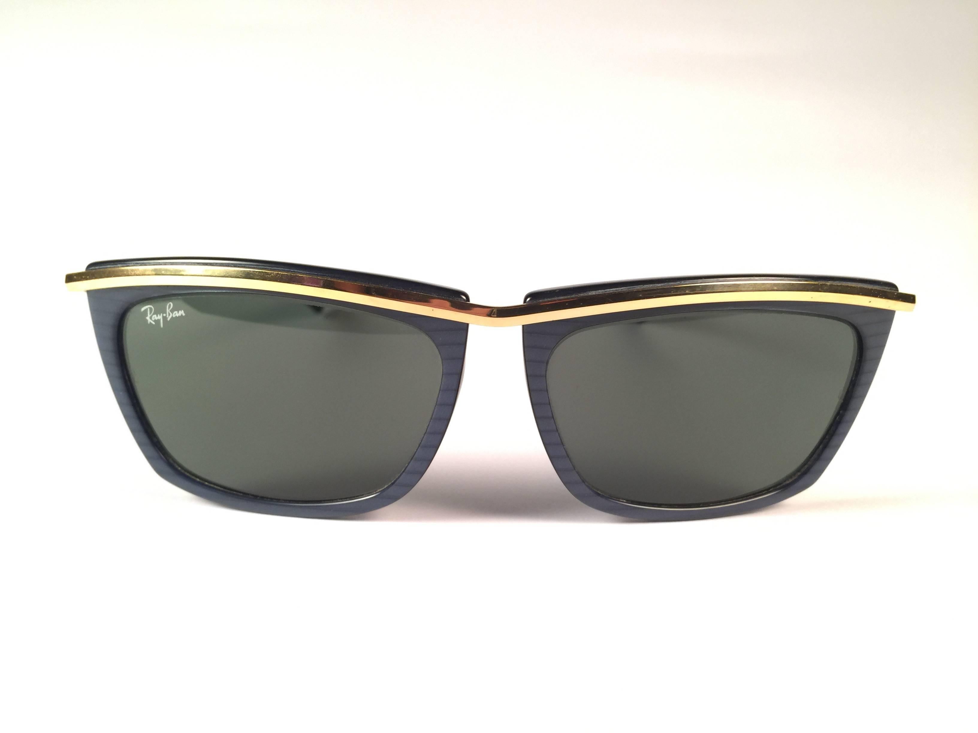 New Vintage Ray Ban Olympia gold and blue frame holding a pair of G15 grey lenses.

New, never worn or displayed. This pair show minor sign of wear due to storage.

Designed and produced in USA.