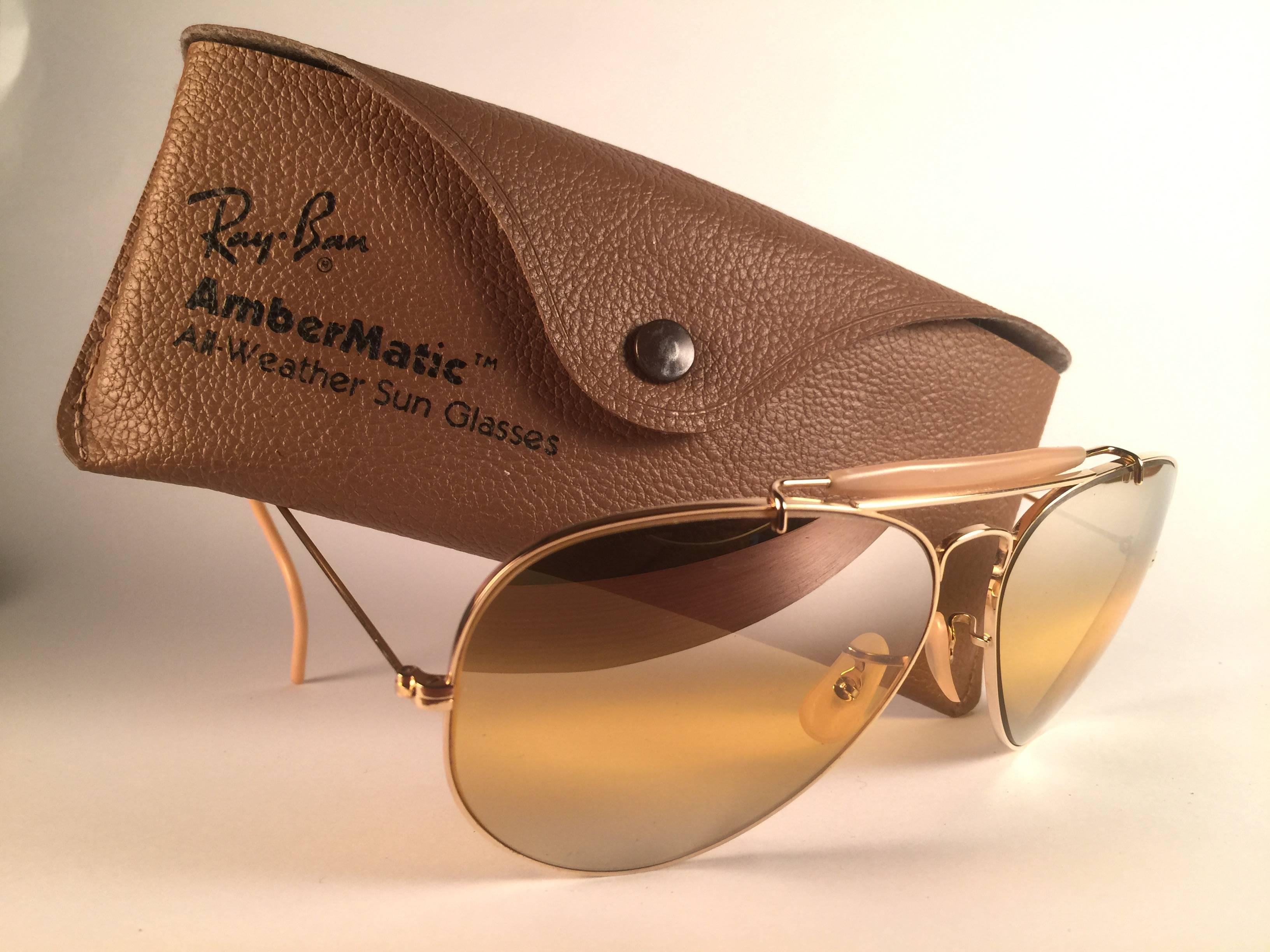 New Vintage Ray Ban Aviator Gold 62mm mit Doppelspiegel Ambermatic Gläser.  B&L ist zweimal in beide Gläser geätzt.  Wird mit dem Original-Etui von Ray Ban B&L geliefert. Bitte beachten Sie, dass dieses Paar aufgrund der fast 40-jährigen Lagerung