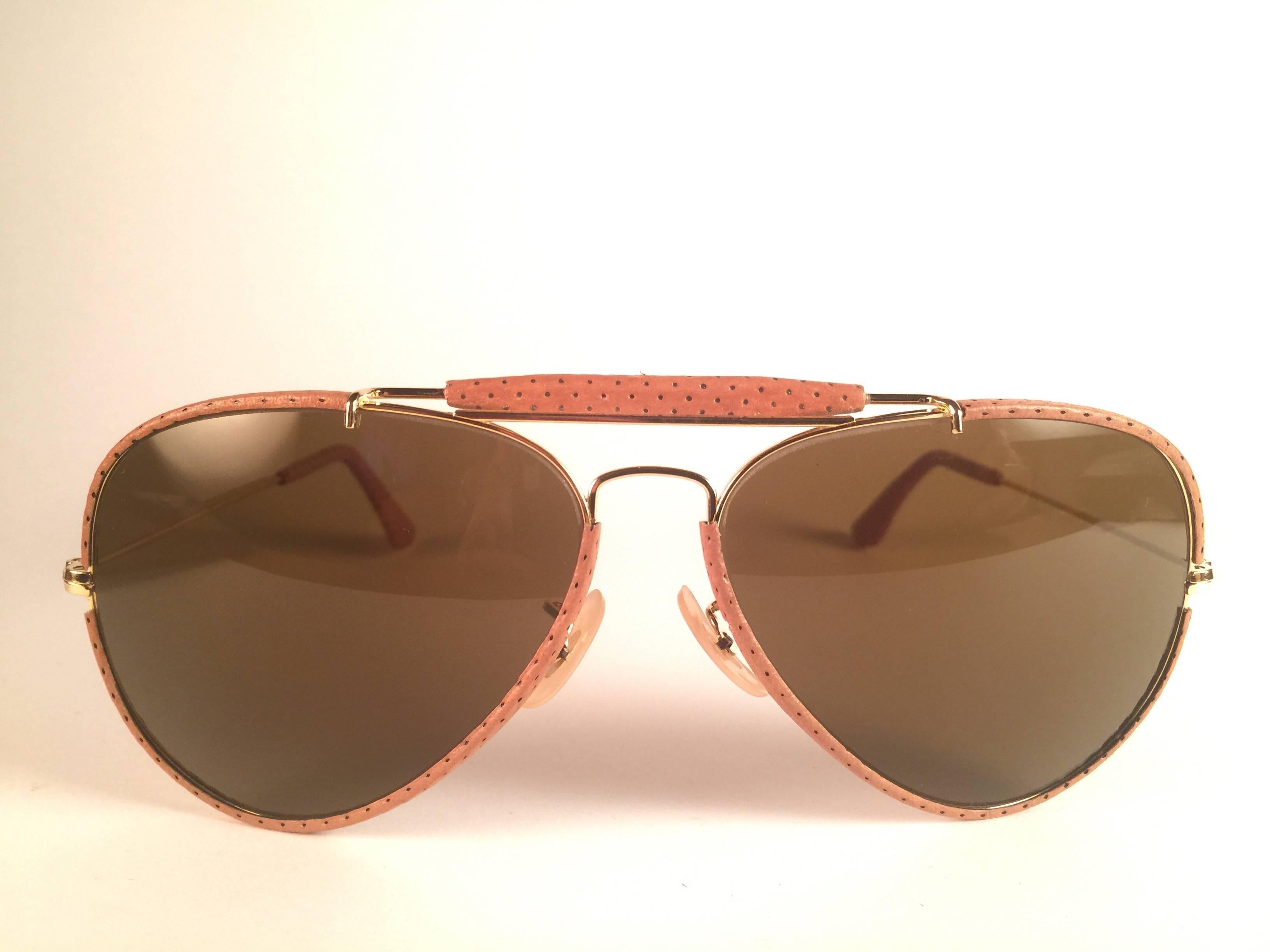 New Vintage Ray Ban Leathers Outdoorsman 62mm in perforated beige leather with gold metal combination frame sporting solid brown lenses.

Comes with its original Ray Ban B&L case with minor sign of wear due to storage. 
Rare and hard to find in this