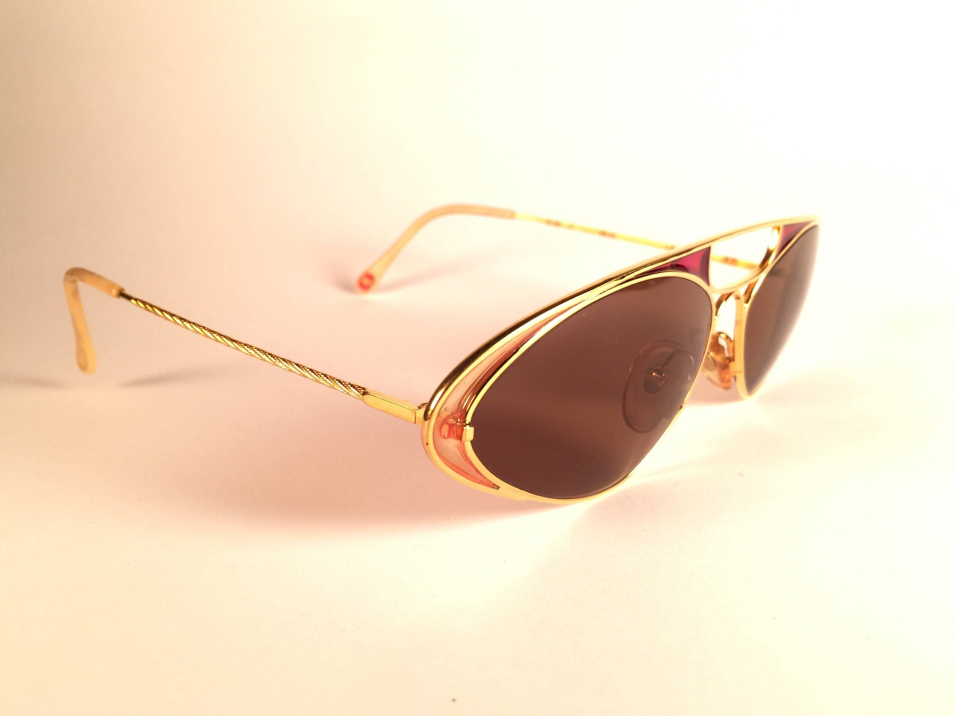 New Vintage Casanova Gold with enamel details frame holding a pair of solid brown lenses.

New, never worn or displayed. This pair may show minor sign of wear due to storage.

Made in Italy.