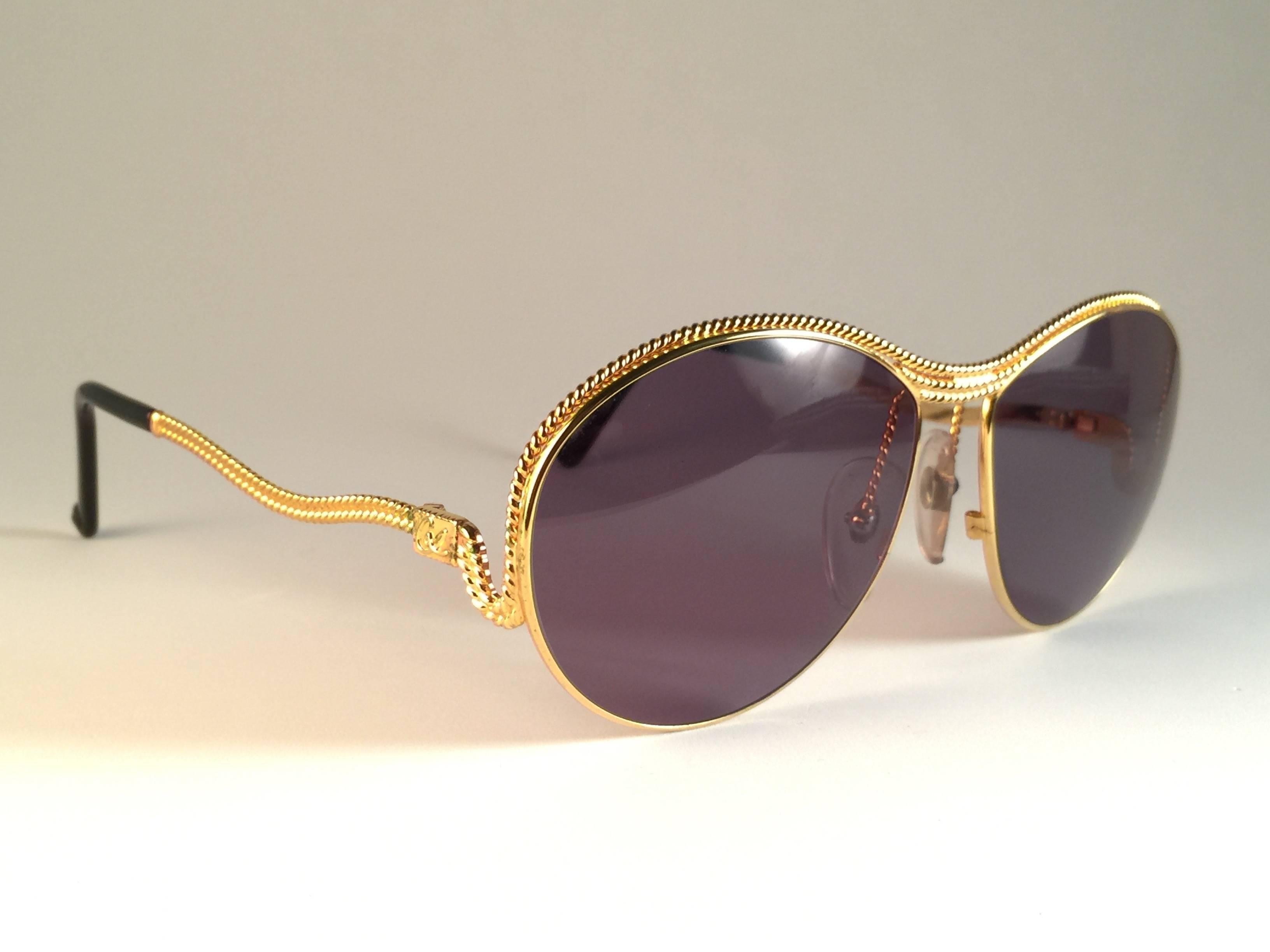 Superb & rare pair of New vintage Christian Lacroix sunglasses.    

Round with delicate gold accents frame holding a pair of grey  lenses.   

New, never worn or displayed. Please notice this item its nearly 40 years old and may show minor sign of