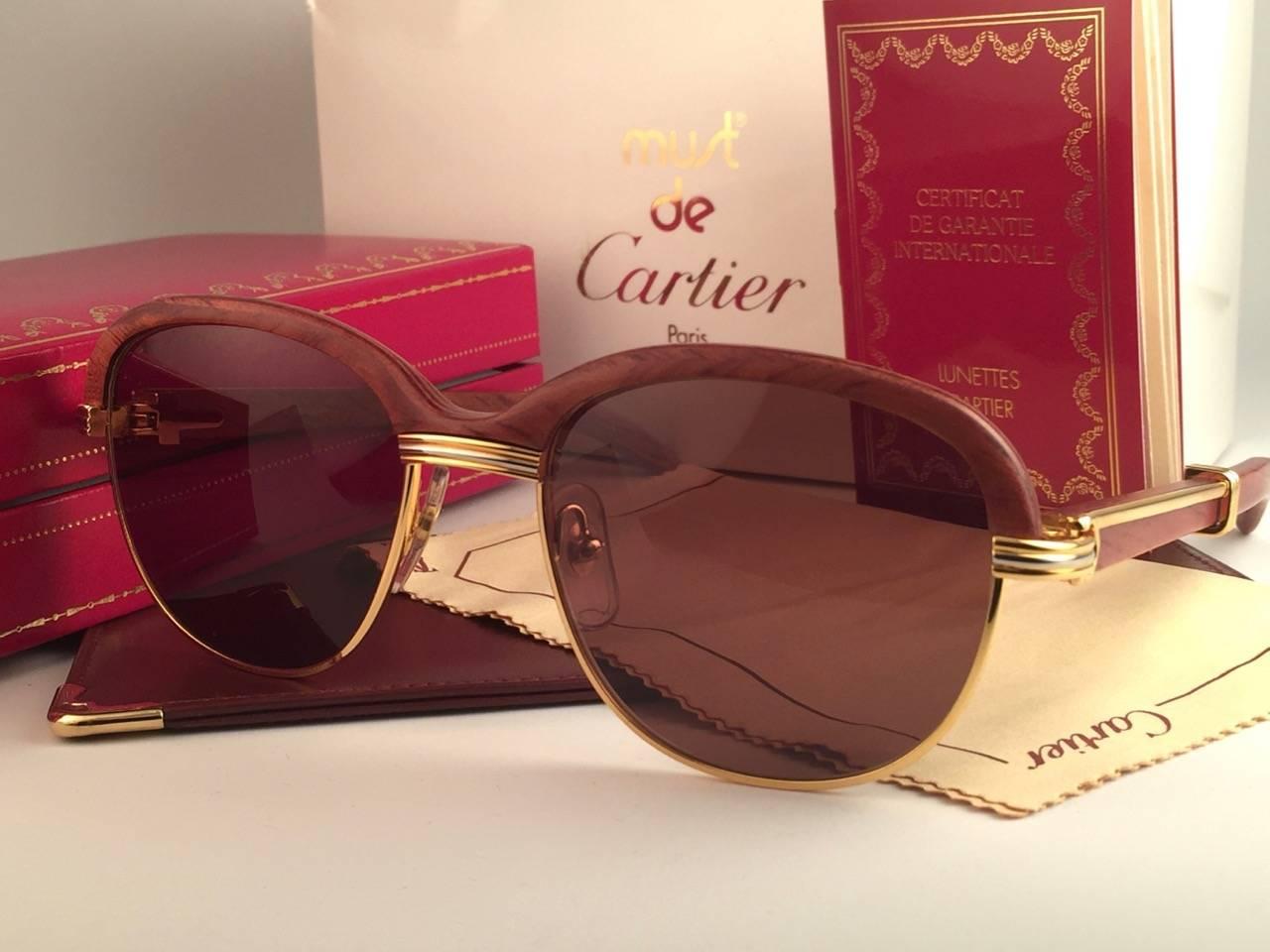 Original New 1990 Cartier Malmaison Palisander hardwood sunglasses with honey brown(uv protection) lenses.  Front and sides in yellow and white gold and has the famous wooden front. Temples are also Palisander combined with gold.  Amazing