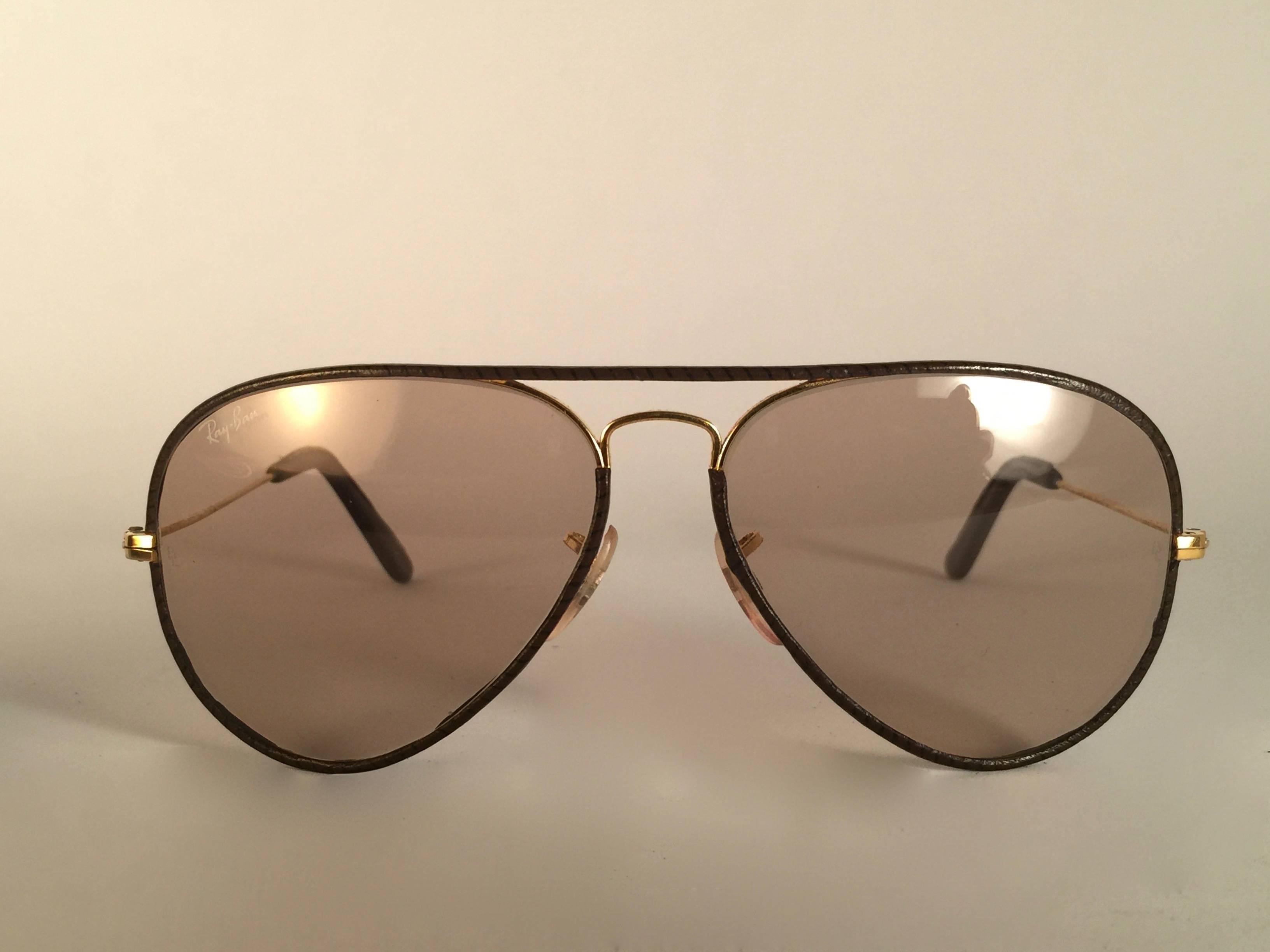 New Vintage Ray Ban Leathers Aviator 58mm in tobacco brown leather with gold metal combination frame sporting light changeable to brown lenses with white Ray Ban logo. B&L etched in the lenses, so mid 1970's. Comes with its original Ray Ban B&L case