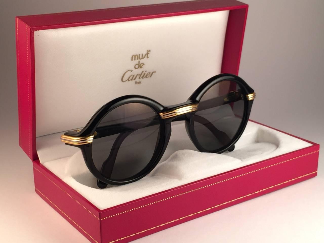 New 1991 Original Cartier Cabriolet Art Deco Black & Gold Sunglasses with grey ( uv protection ) lenses
Frame has the famous real gold and white gold accents in the middle and on the sides. 
All hallmarks. Cartier gold signs on the earpaddles. Both