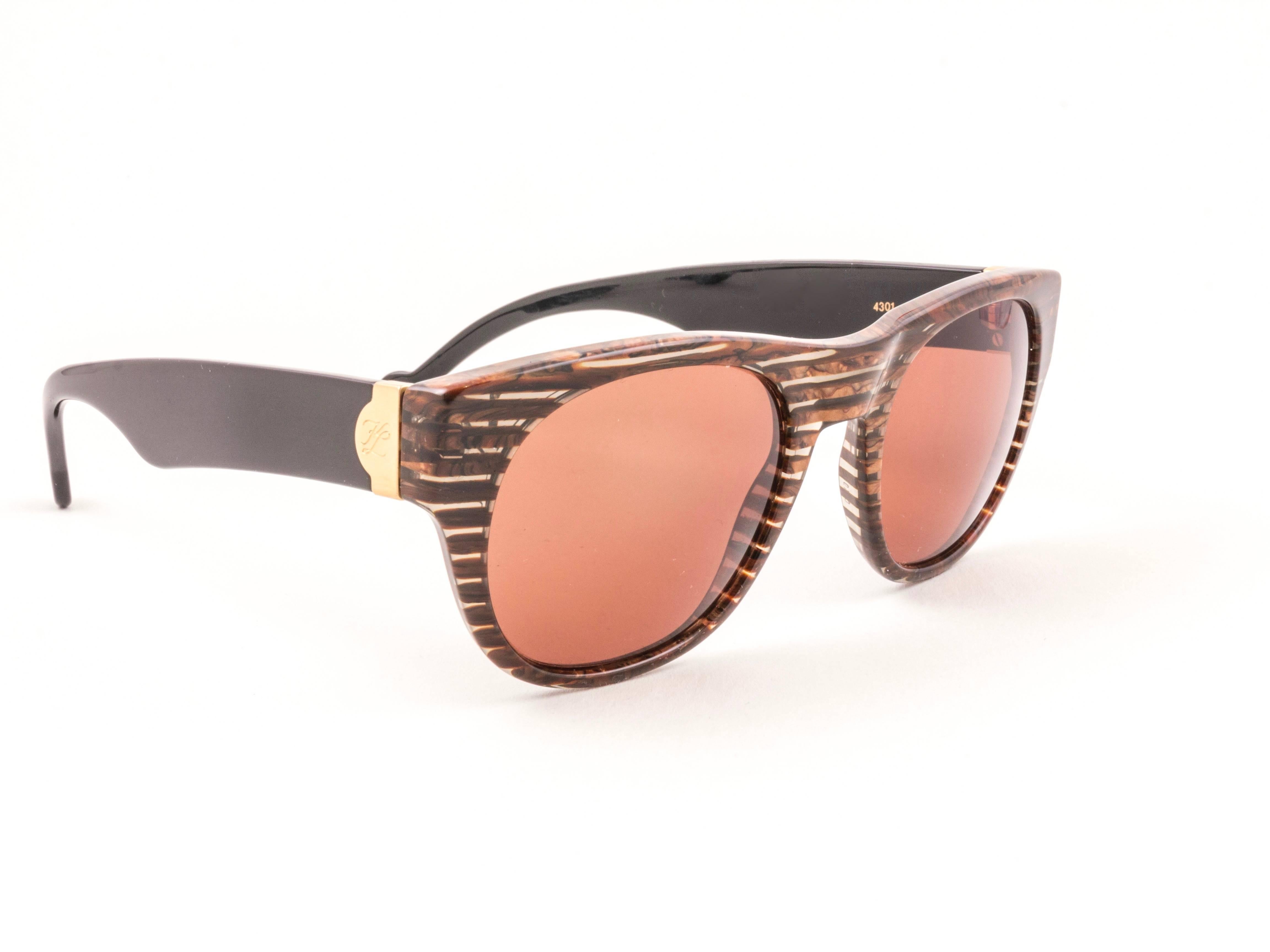 Sturdy pair of vintage Karl Lagerfeld sunglasses brown translucent striped with gold inserts on black temples sporting a spotless pair of dark amber lenses. 

New, never used or displayed this pair of vintage Karl Lagerfeld is an outstanding and
