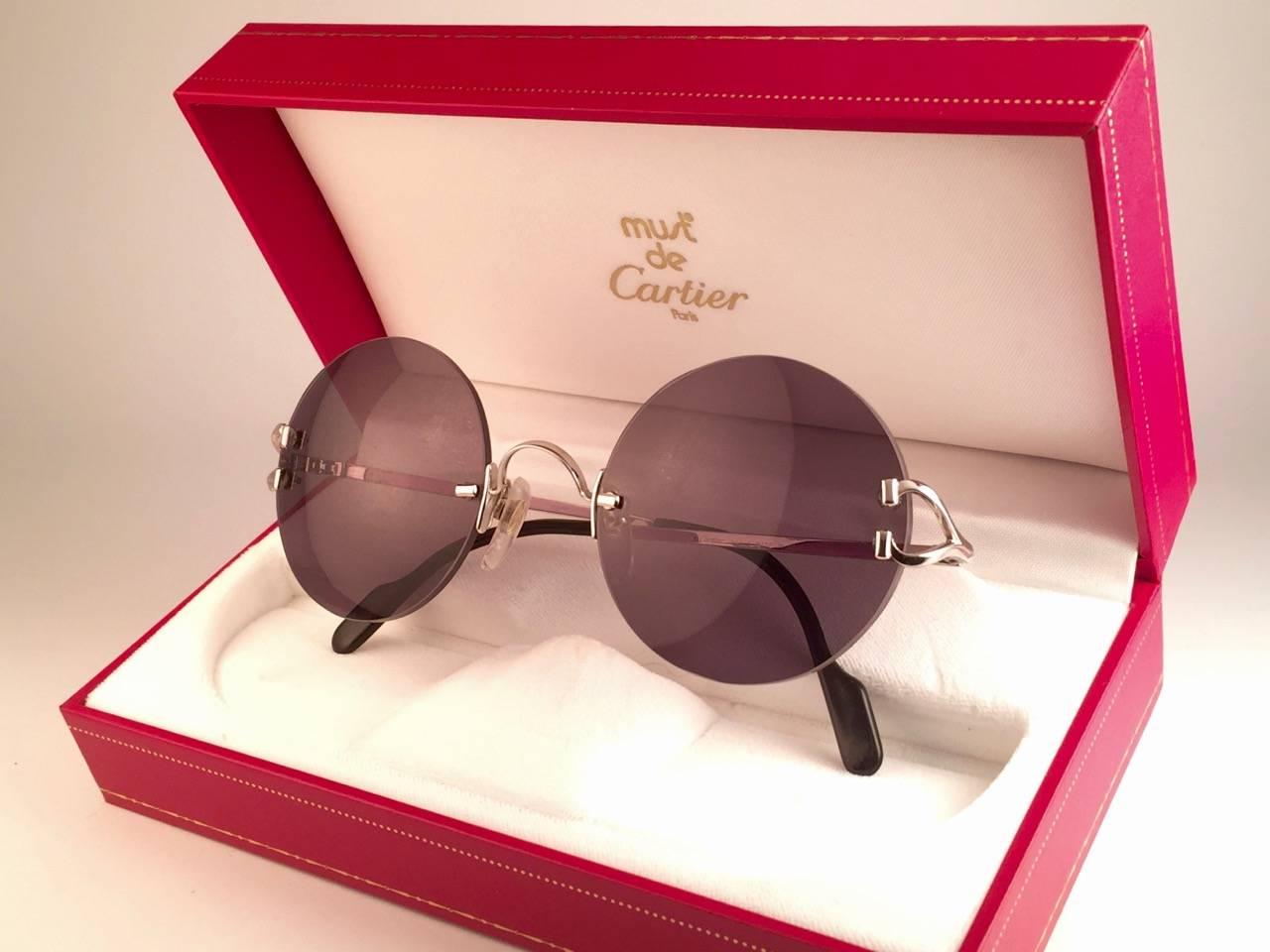 New 1990 Cartier Madison unique rimless sunglasses with grey (uv protection) lenses. 
Frame with the front and sides in Platine. 
Cartier Platine signs on the onyx black ear paddles. 
These are like a pair of jewels on your nose. 
Please notice this