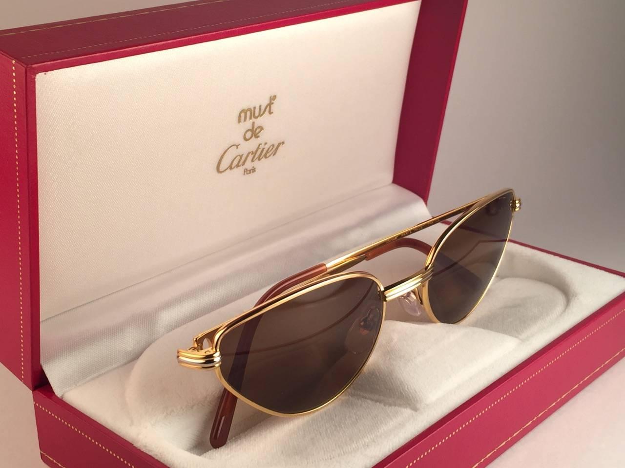 New 1988 Cartier Rivoli Vendome Cat Eye Sunglasses with new honey brown  (uv protection) lenses. The cat's eye frame is with the front and sides in yellow and white gold. All hallmarks. Red enamel ear paddles. Both arms sport the C from Cartier on
