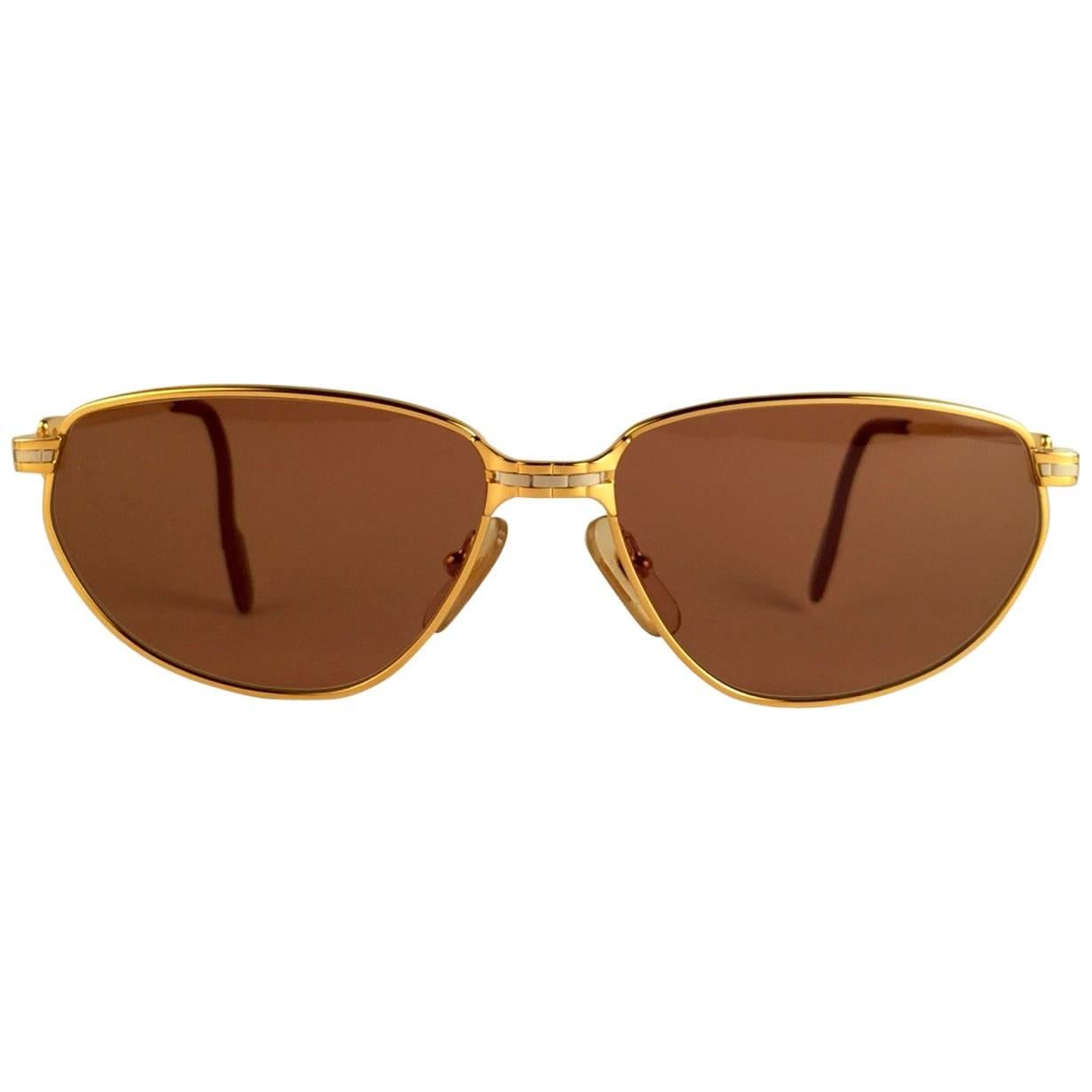 New 1988 Cartier Panthere Windsor Sunglasses with spotless brown(uv protection) lenses. The cat's eye frame is with the front and sides in yellow and white gold. All hallmarks. Red enamel ear paddles. 
Both arms sport the C from Cartier on the