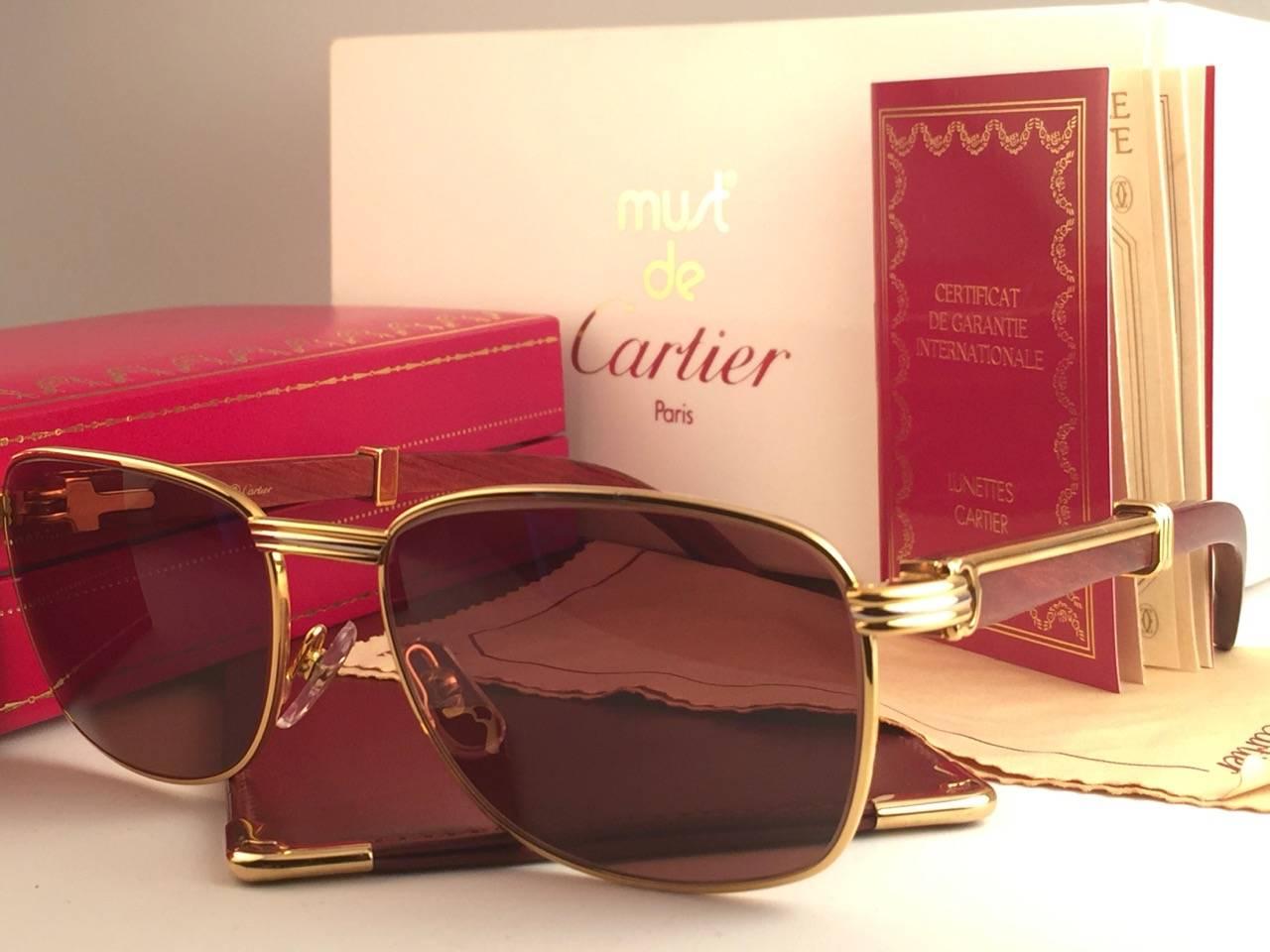 New 1990 Cartier Full Set Amboise Bubinga Hardwood Sunglasses with new solid honey brown (uv protection) lenses. 
Frame is with the front and sides in yellow and white gold and has the famous wood & gold accents temples. 
Amazing craftsmanship! All
