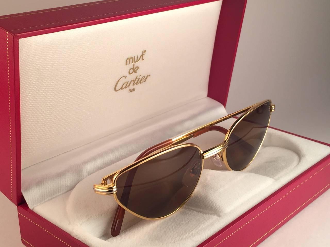New 1988 Cartier Rivoli Vendome Cat Eye Sunglasses with new honey brown  (protection contre les UV). La monture œil de chat est avec le devant et les côtés en or jaune et blanc. Tous les poinçons. Palettes d'oreilles en émail rouge. Les deux bras