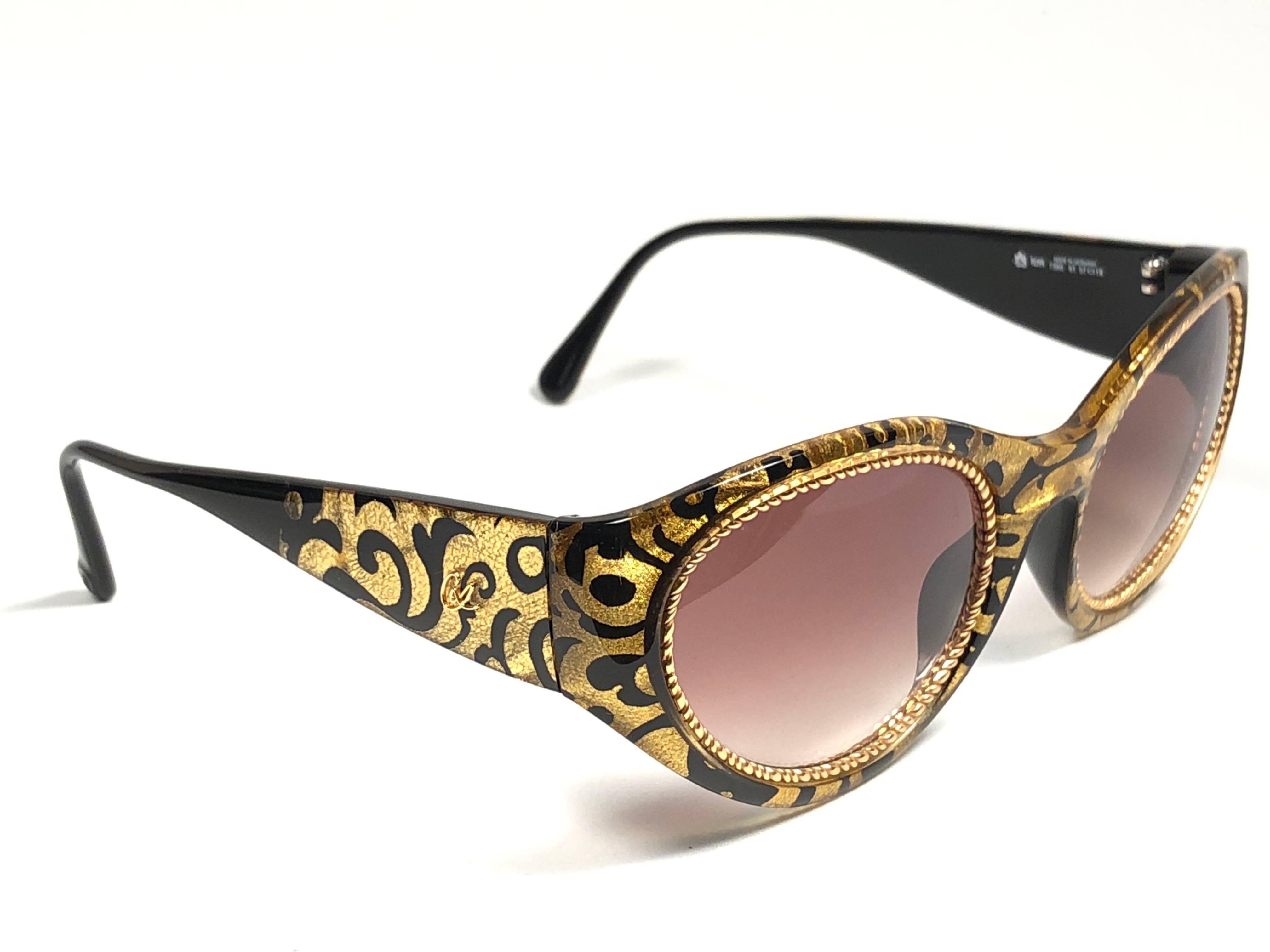 Rare pair of New vintage Christian Lacroix sunglasses.   

Black & gold baroque pattern frame holding a pair of spotless amber mirror lenses. The interior logo has fade due to storage.

New, never worn or displayed. 

Made in France.