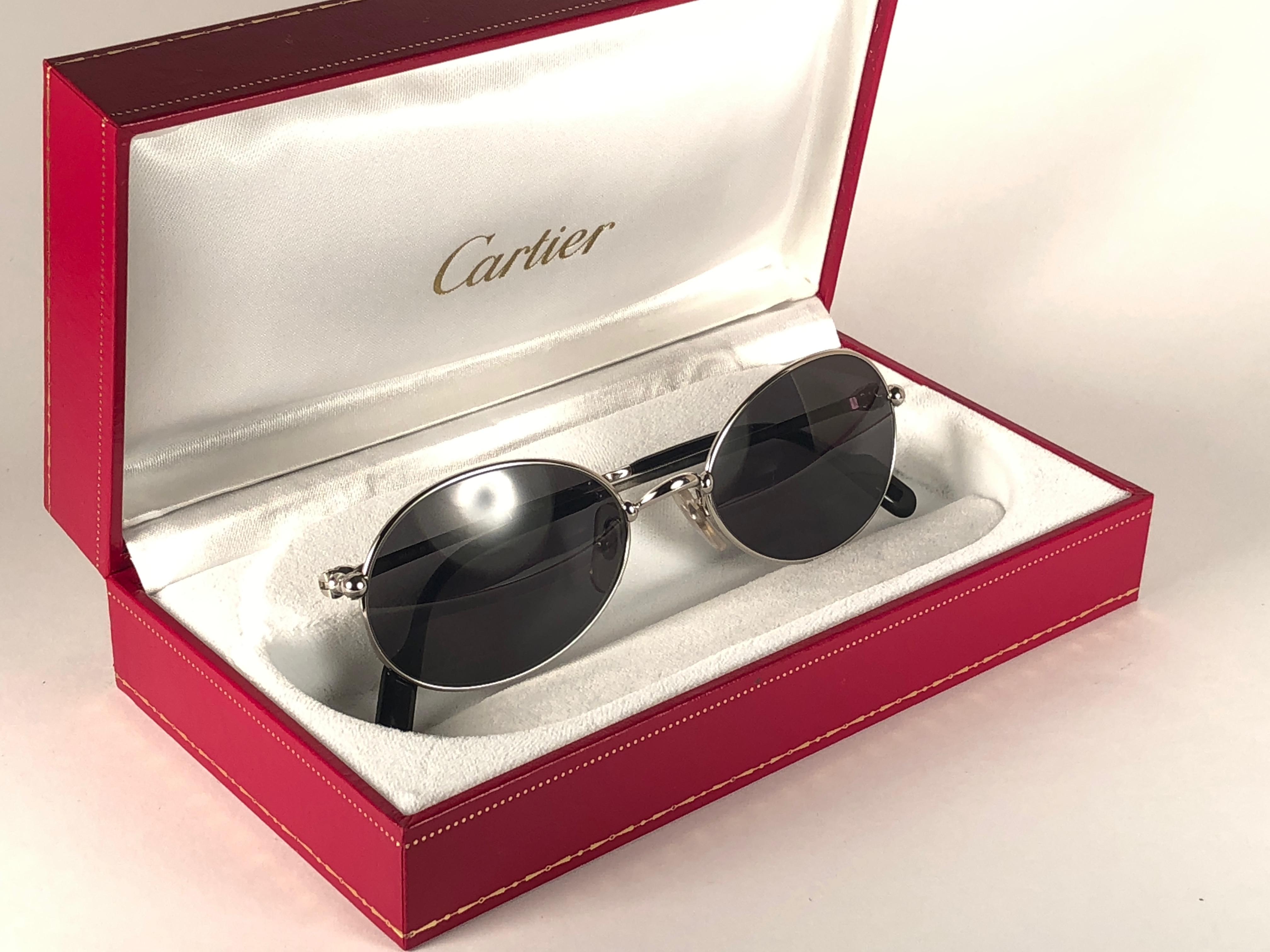 1990 Cartier Saturne Sonnenbrille mit grauen (uv-Schutz) Gläsern.  Alle Markenzeichen.  Cartier-Silberzeichen auf den Ohrpolstern.  
Sie sind wie ein Paar Juwelen auf der Nase. 
Bitte beachten Sie, dass dieses Paar fast 30 Jahre alt ist und leichte