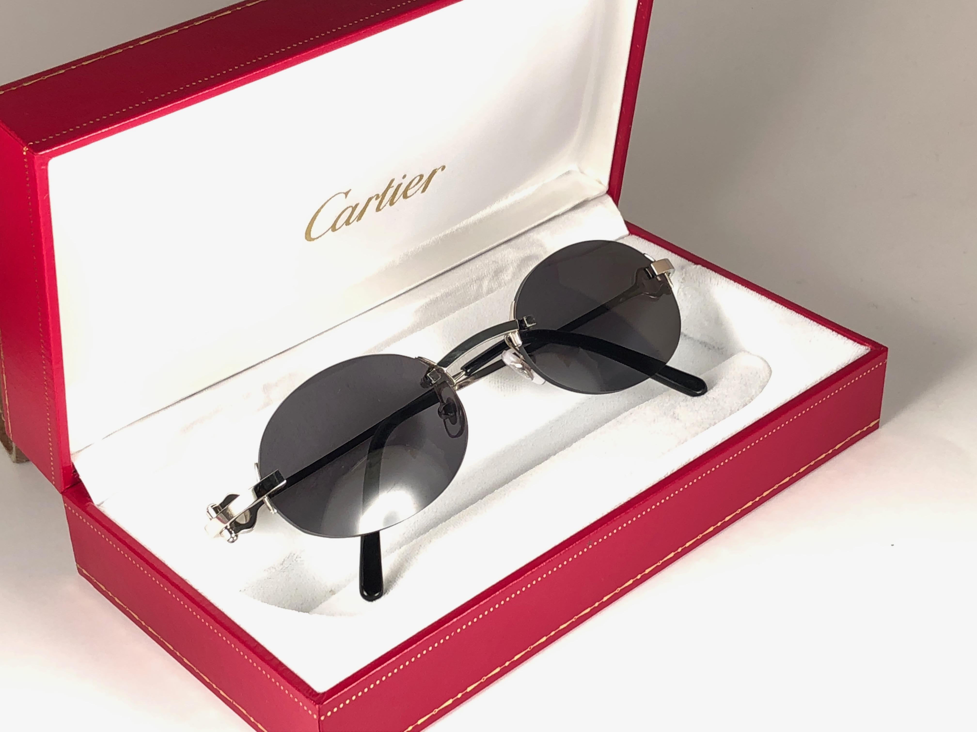 New 1990 Cartier Shamal unique rimless sunglasses with grey (uv protection) lenses. Frame with the front and sides in platine. All hallmarks. 

Cartier gold signs on the black ear paddles. 

Please notice this item its nearly 30 years old and may