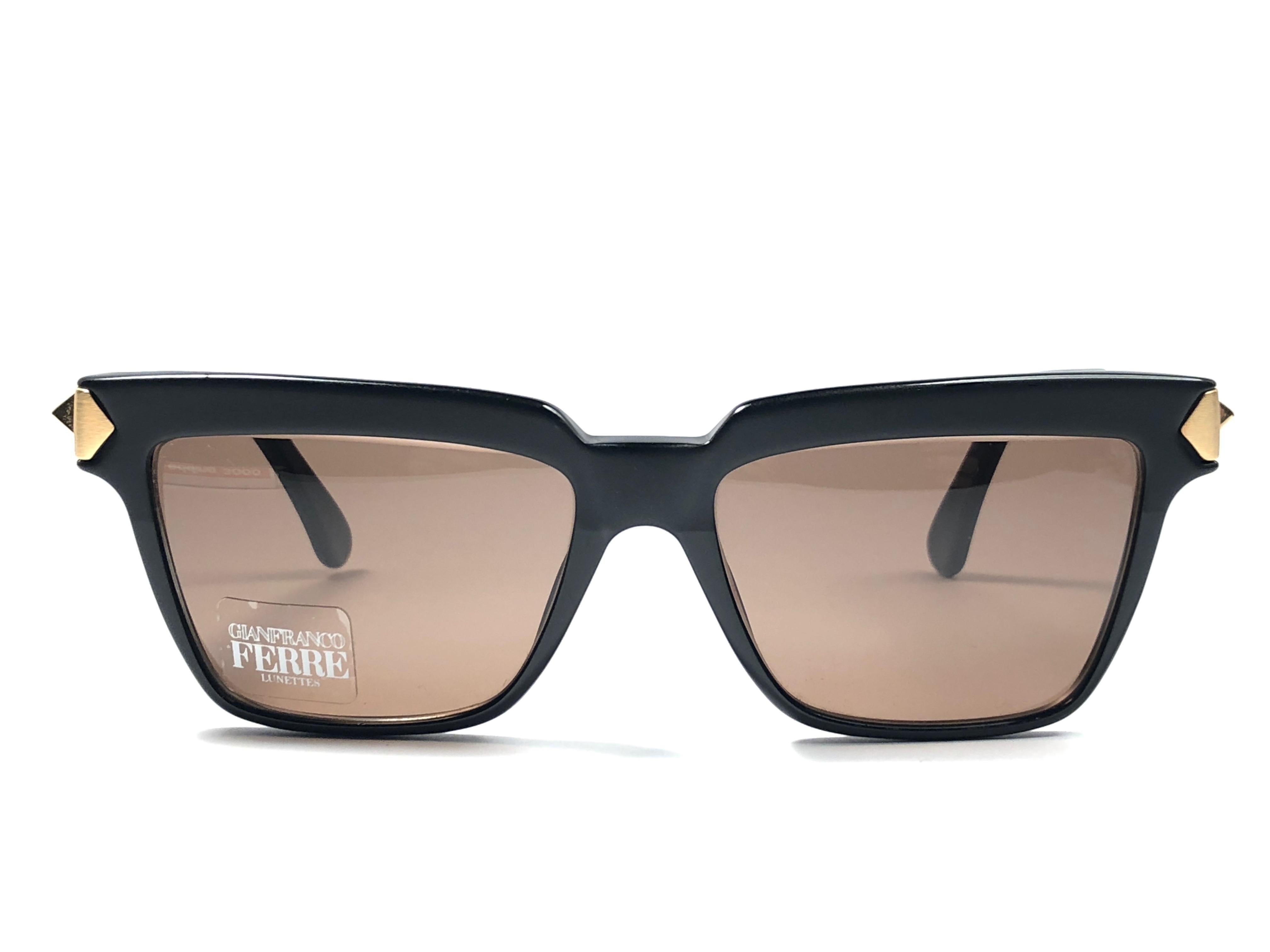 Nouvelles lunettes de soleil vintage Gianfranco Ferre.    

Monture noire avec des détails dorés tenant une paire de verres gris immaculés.   

Neuf, jamais porté ou exposé. 

 Fabriquées en Italie.