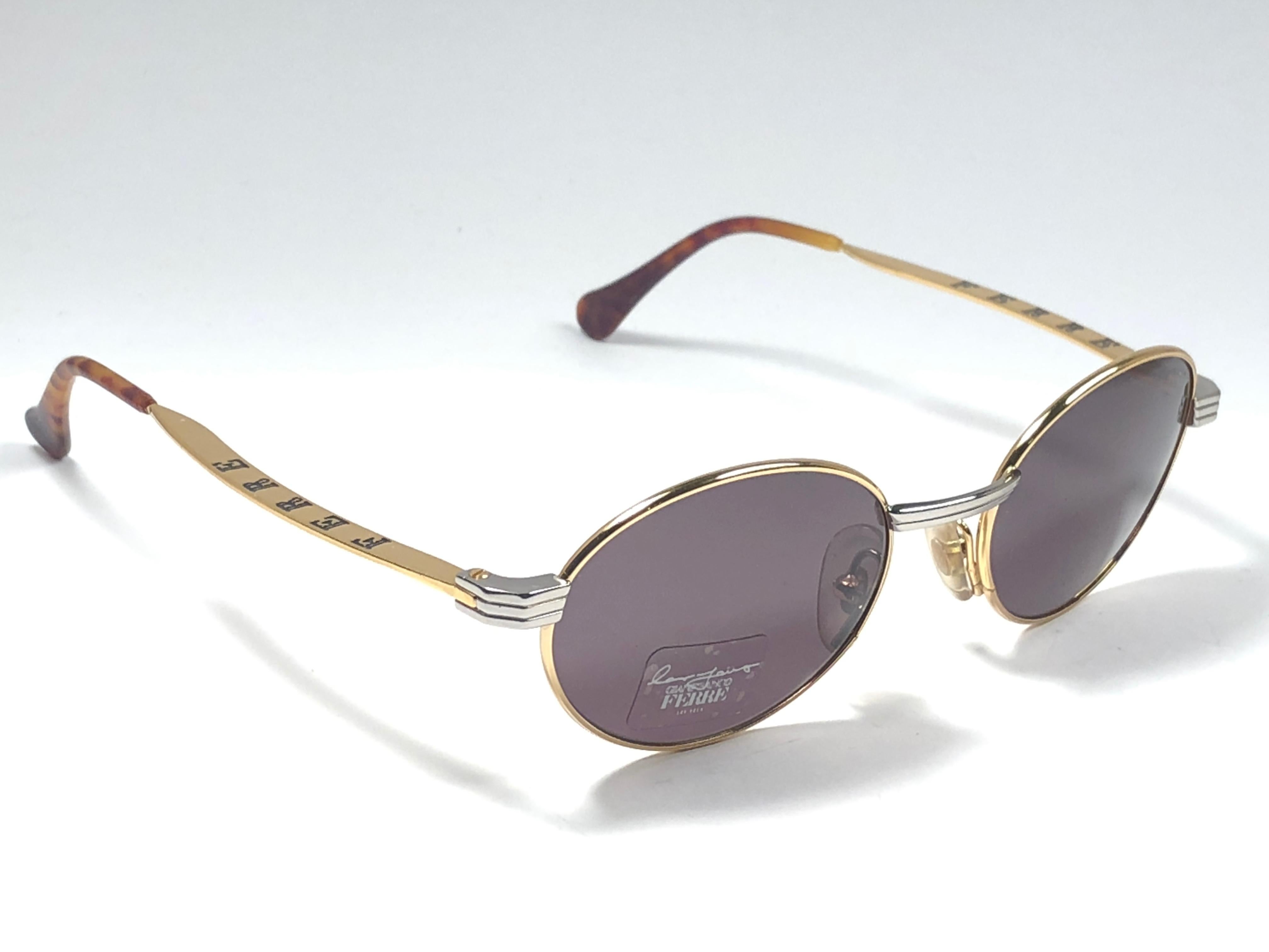 New vintage Gianfranco Ferre sunglasses.    

Gold and silver details frame holding a pair of spotless grey lenses.   

New, never worn or displayed. 

 Made in Italy.