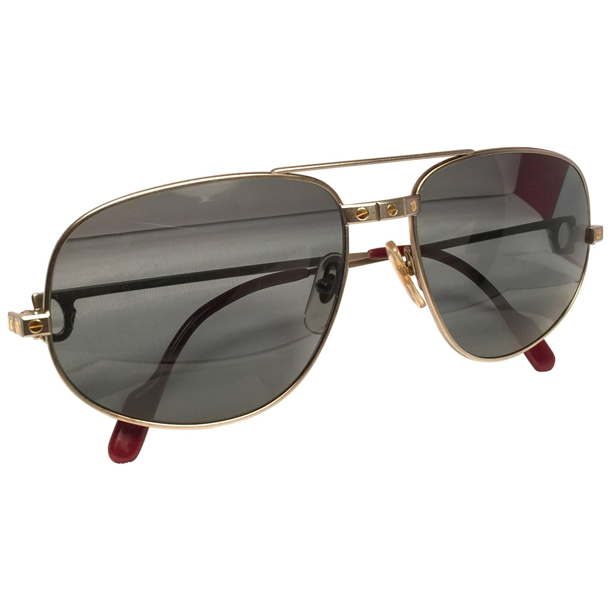 Occhiali da sole vintage Cartier Romance Santos in titanio con lenti grigie sfumate (protezione UV). La cornice ha il fronte e i lati in oro giallo e bianco. Tutti i segni distintivi. Smalto rosso con segni di Cartier in oro sulle palette delle