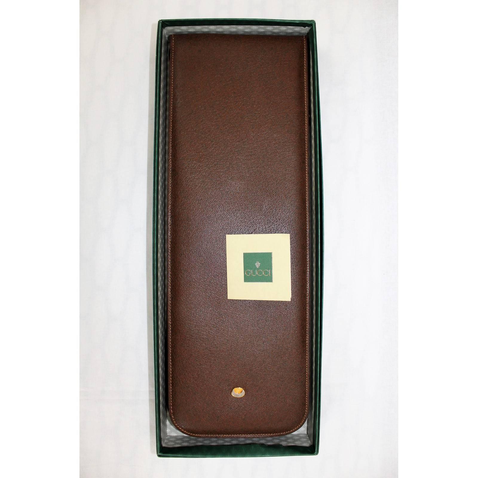Gucci travel tie holder (1980), with original box and authenticity tag Brown leather, green velvet lining, internal gilt-metal tie rack Excellent vintage conditions, as new.

Measurements:
Length: 43 cm.
Width: 15 cm.

Material: Leather
Colour: