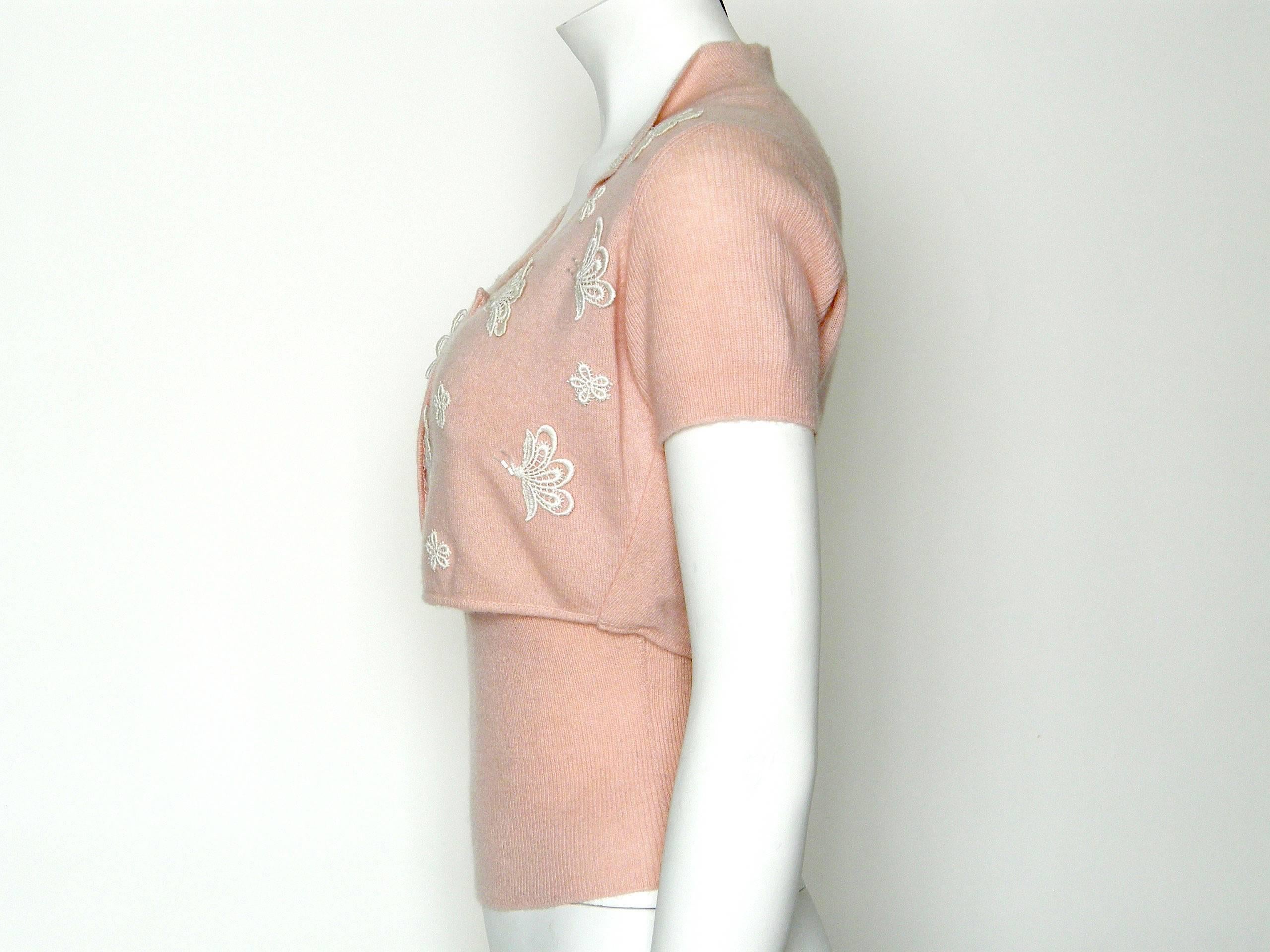 This charming sweater set is a pale, warm pink cashmere decorated with appliquéd flowers and butterflies with beaded accents. The fitted tank top has slender shoulder straps and an elongated, rib knit waist with a nice peaked detail under the