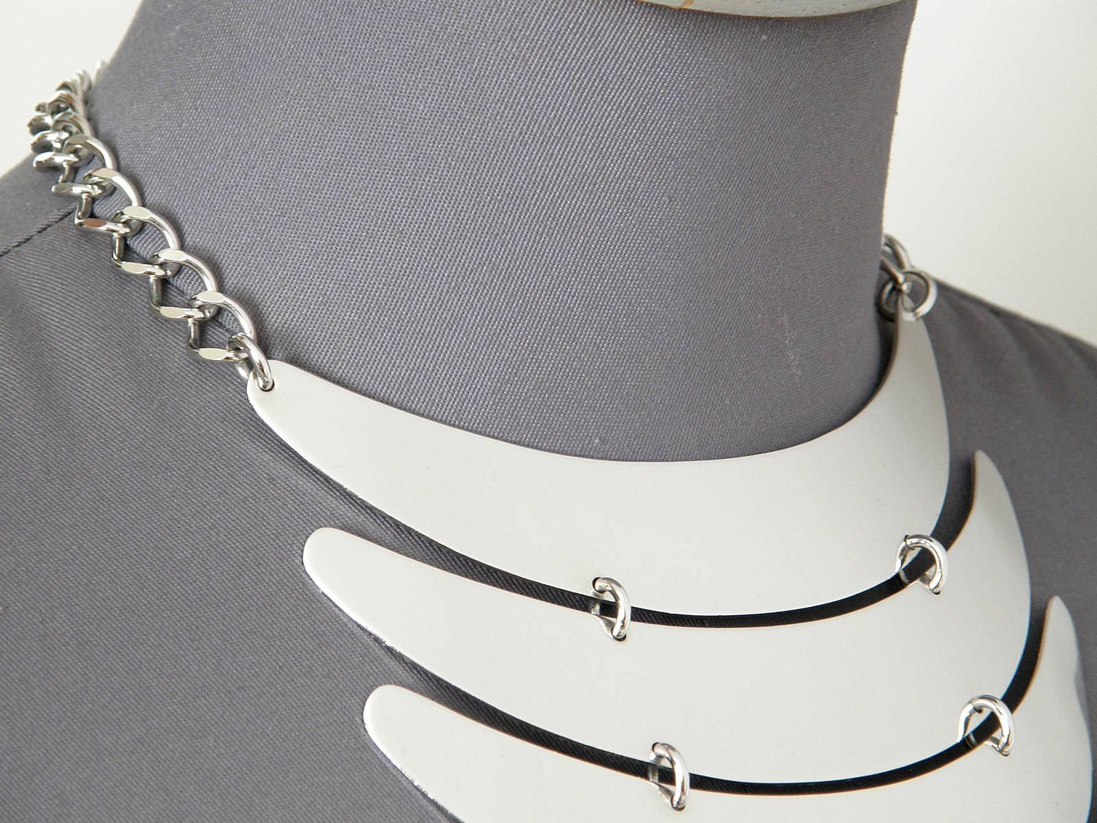 This modernist breastplate necklace is from a space age style line of jewelry by Trifari. It's constructed from five streamlined crescent shaped pieces of chrome plated metal that are hinged together. It has a great period look.

each plate measures