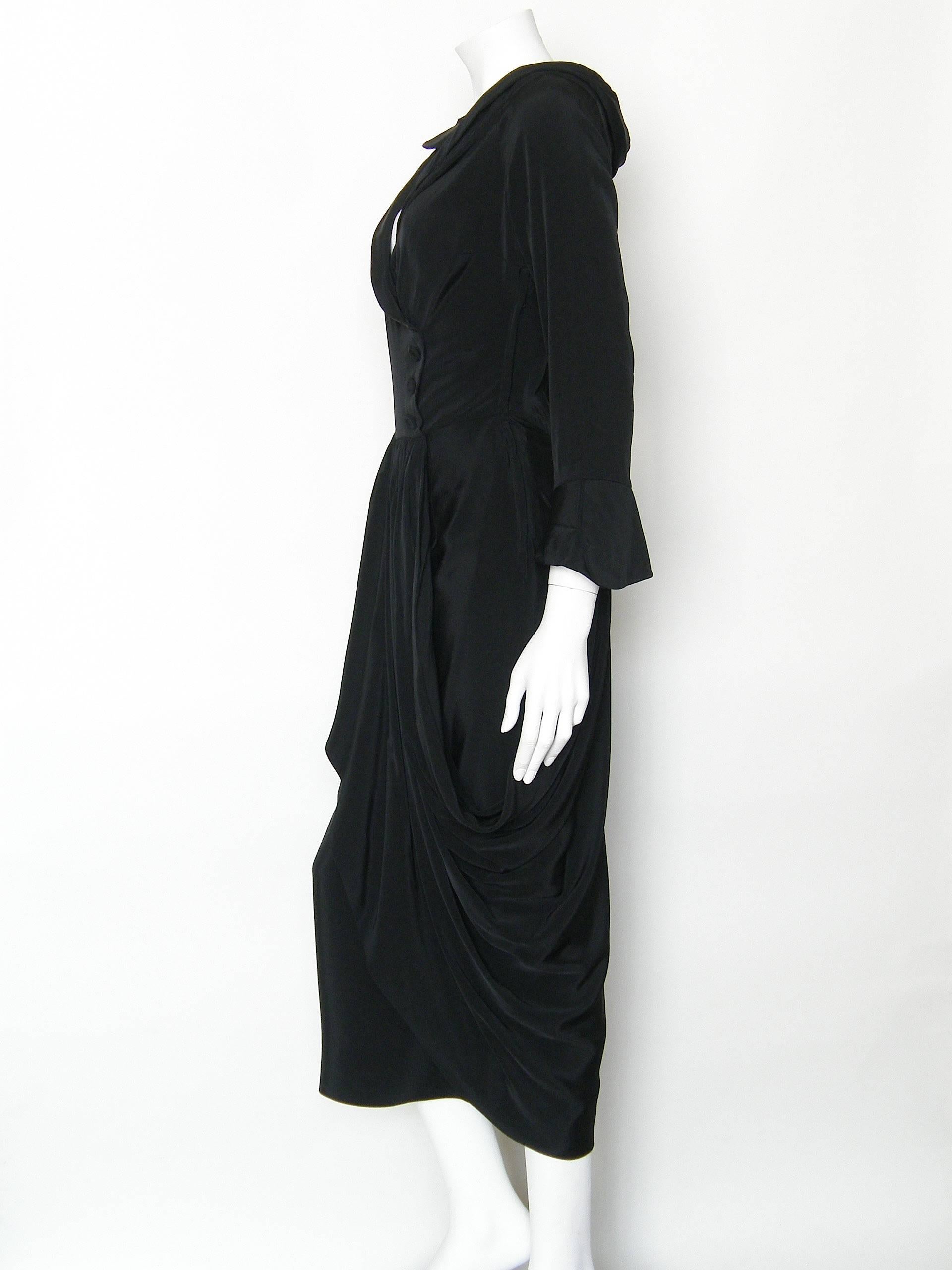 This beautifully constructed Ceil Chapman cocktail dress is very figure flattering. It has a fixed wrap cut with non-functioning buttons down the left side of the bodice, a portrait neckline, extravagant draping on the skirt, and long split cuffs on